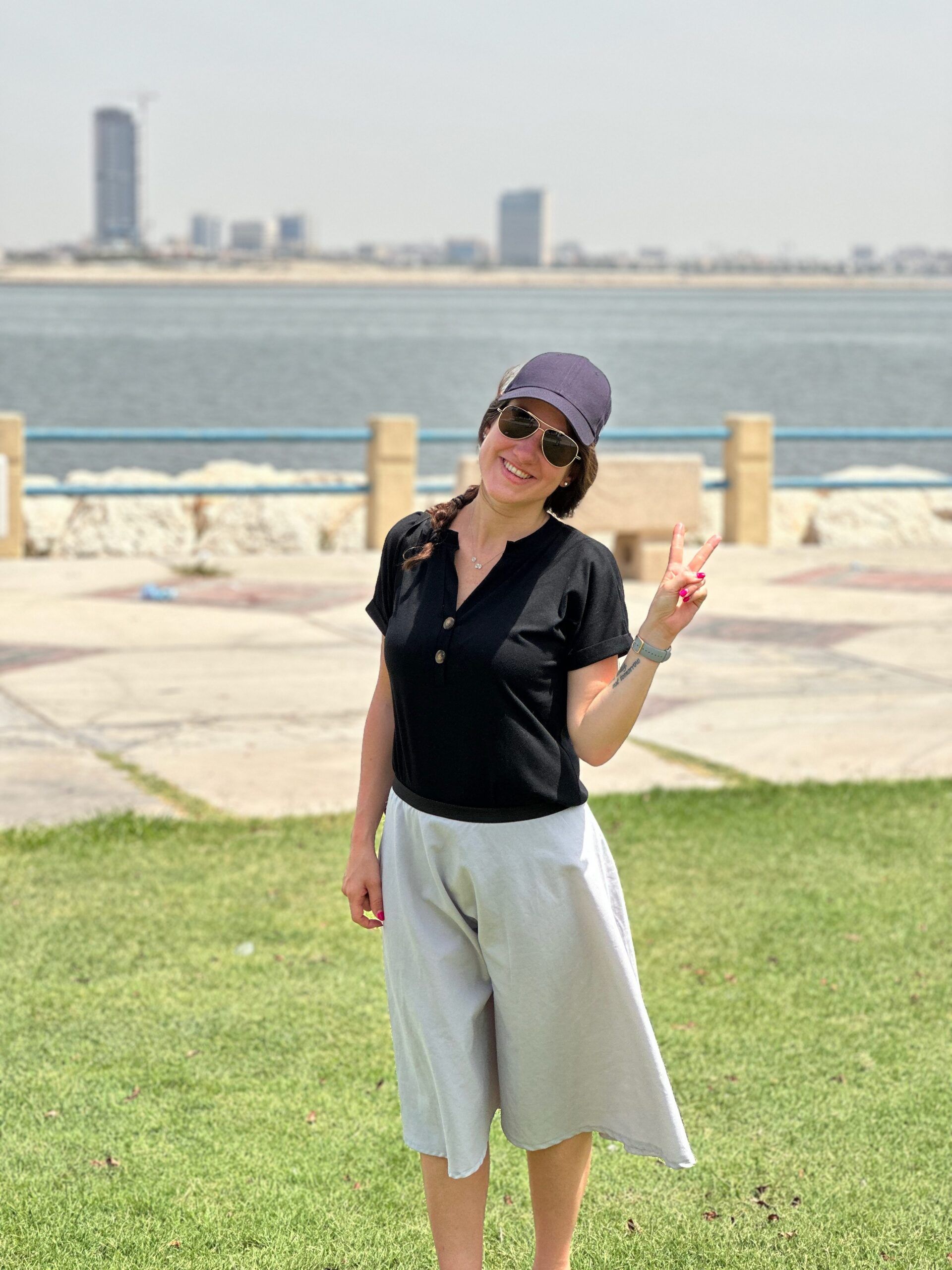 Kobieta na trawniku nad wodą w dammam khobar sea front, pokazuje znak v.