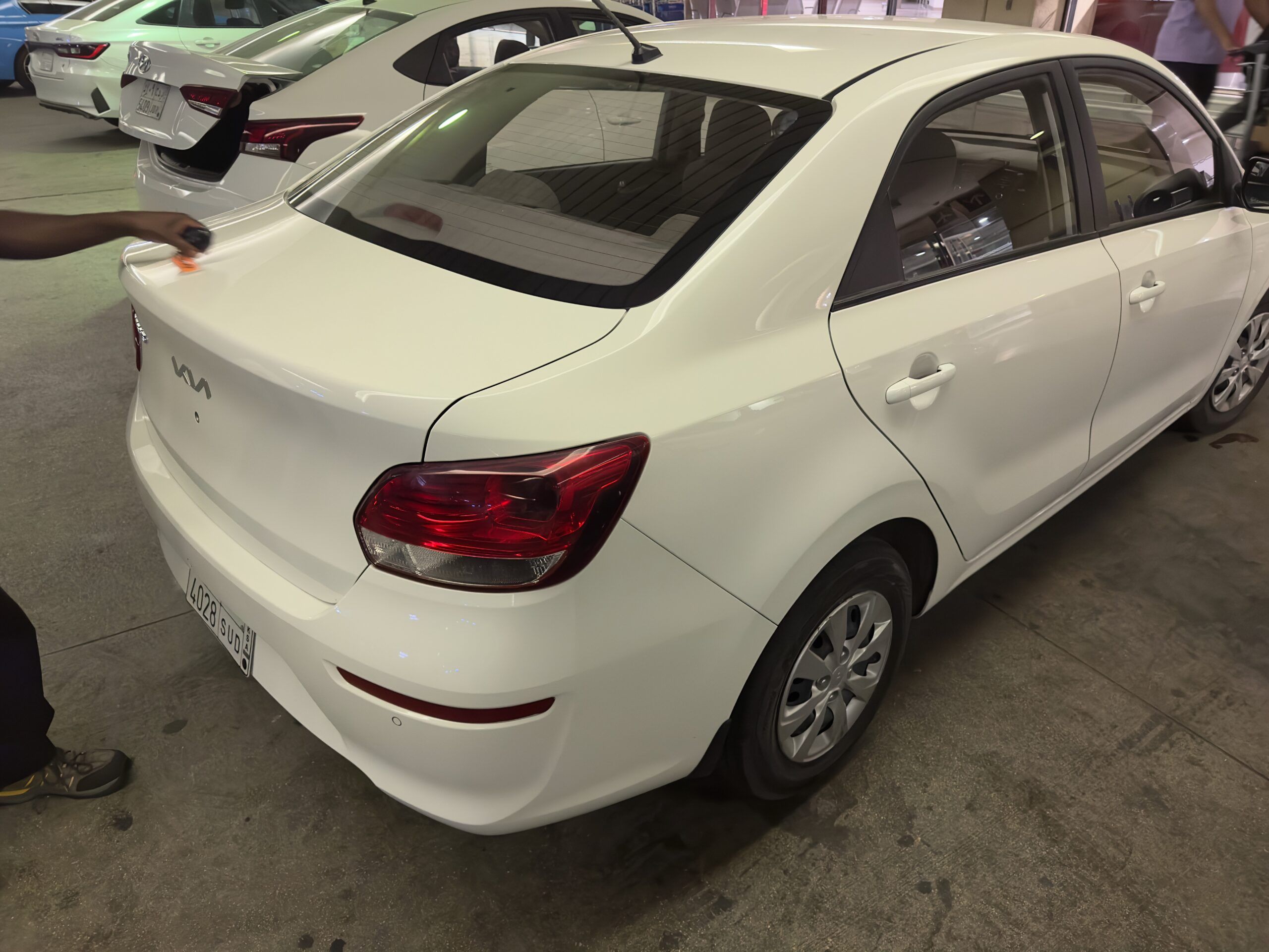 White sedan being cleaned, with other cars parked in saudi arabia.