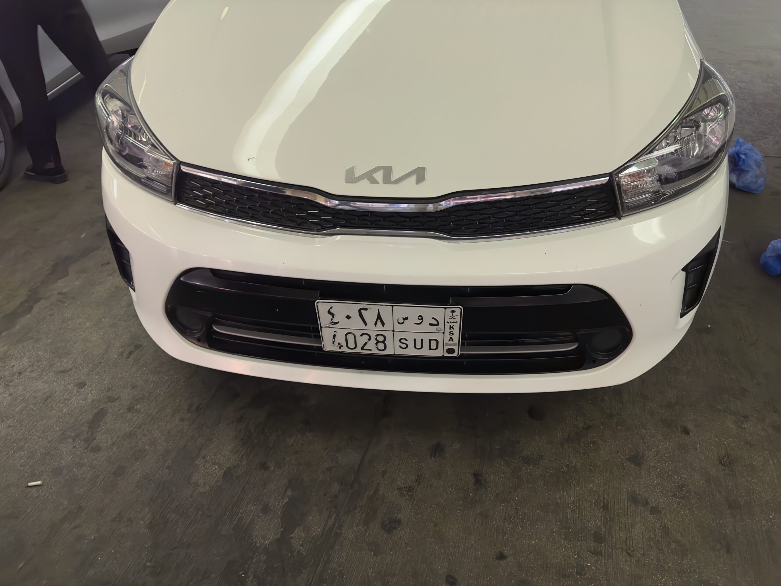 Front view of a white kia car with a saudi arabia license plate indoors