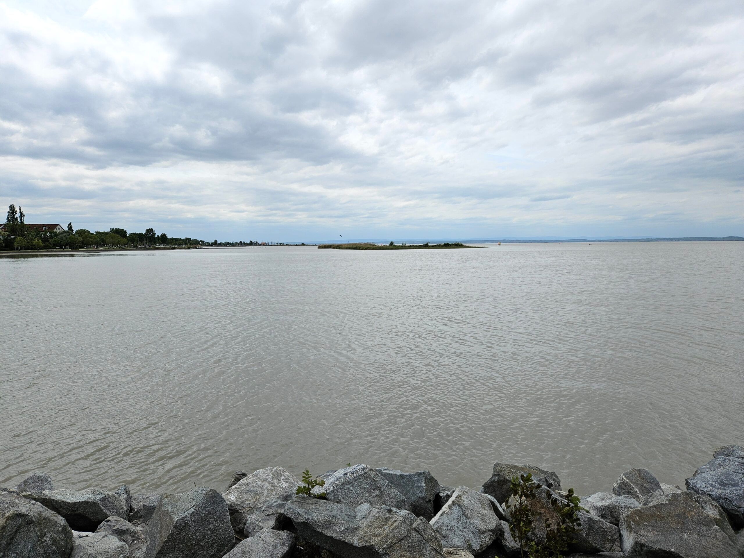 Widok na latarnię w podersdorf nad jeziorem, z kamienistym brzegiem i pochmurnym niebem