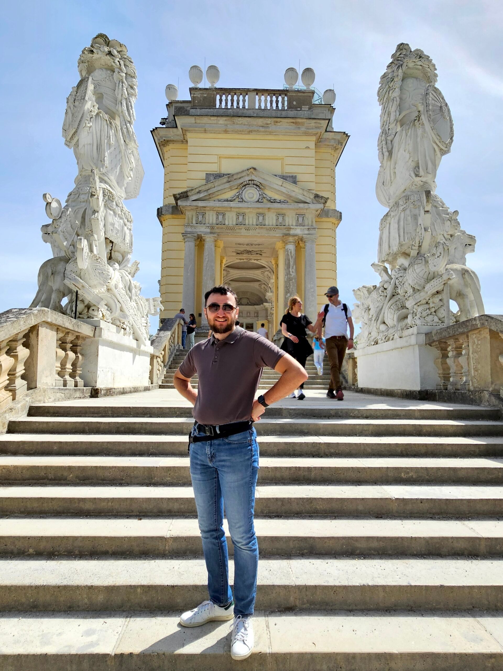 Gloriette w wiedniu z rzeźbami przy schodach i turystą na pierwszym planie