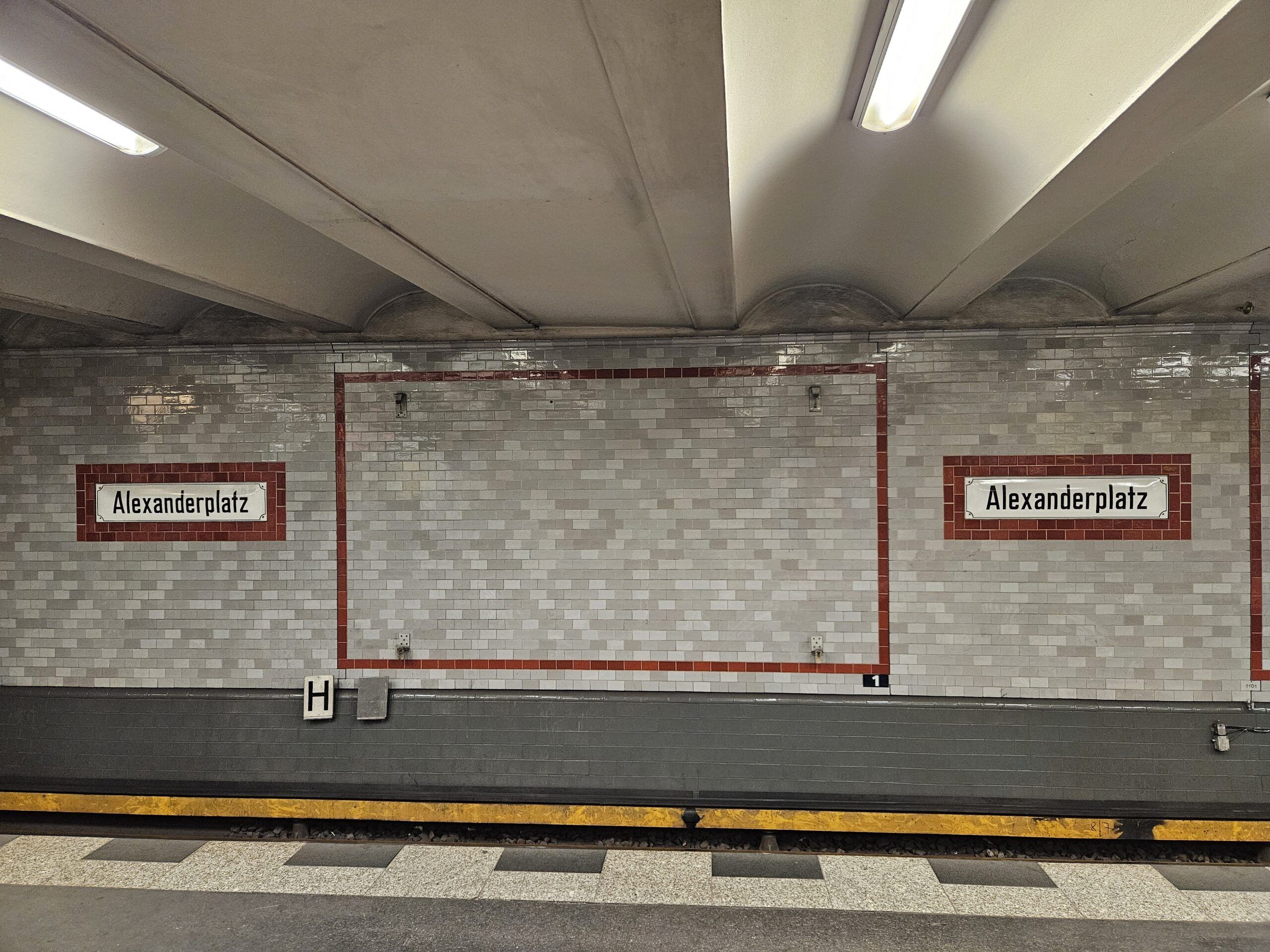 Peron metra alexanderplatz w berlinie z białymi kafelkami i czerwonym obramowaniem