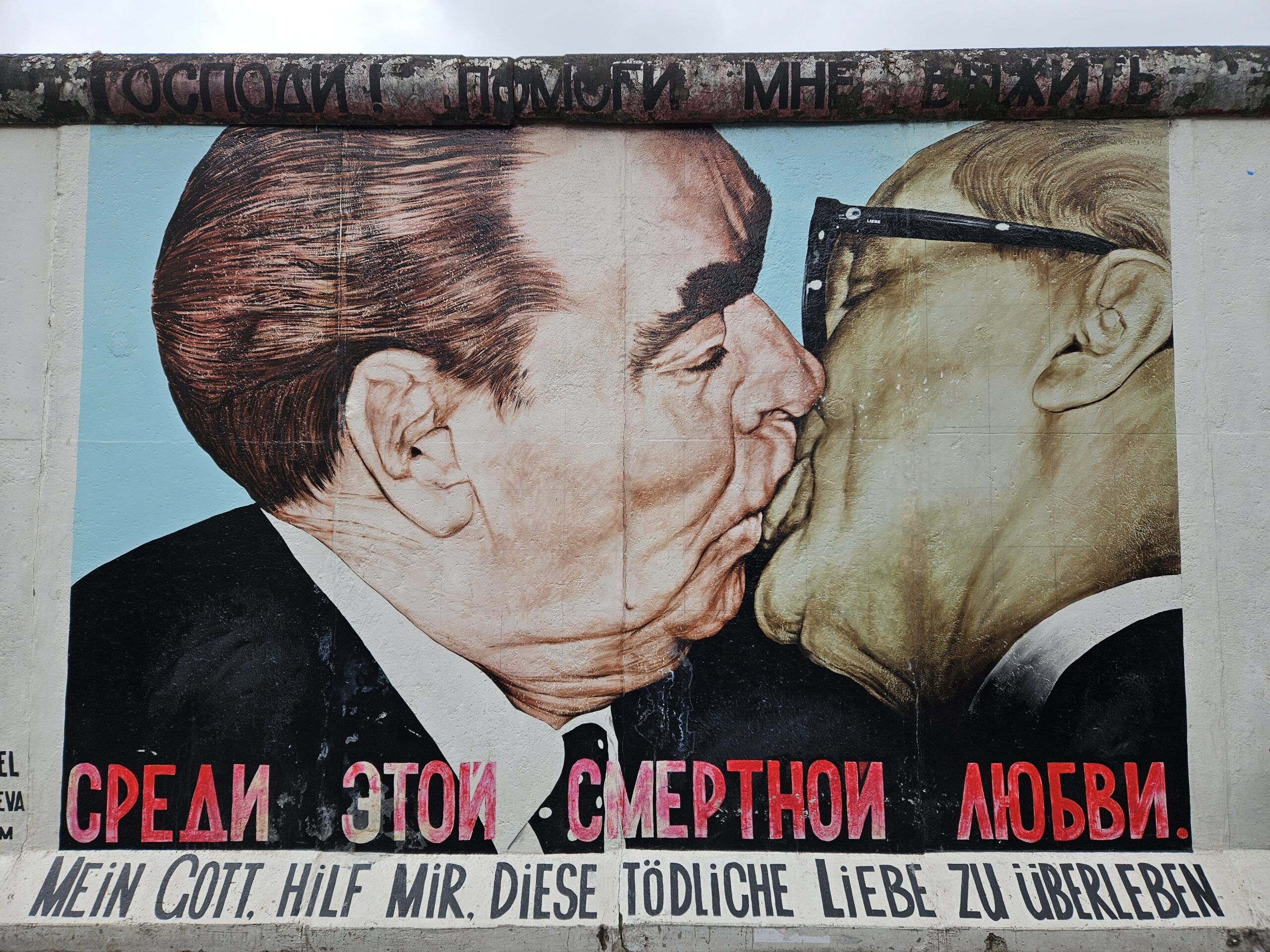 Mural na murze berlińskim w berlinie z całującymi się przywódcami i napisem po niemiecku.