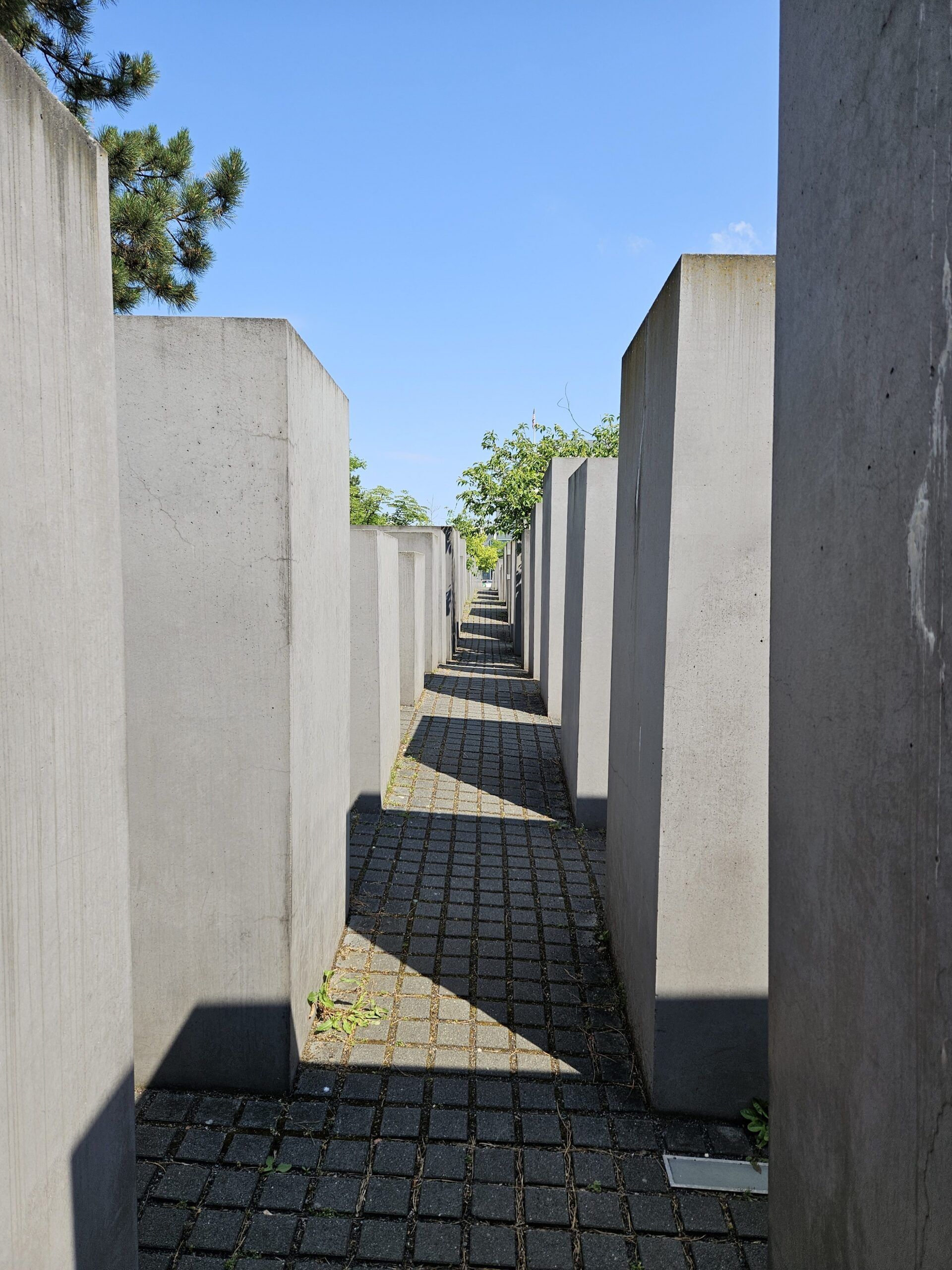 Pomnik pomordowanych żydów europy w berlinie, wąski korytarz między betonowymi blokami pod błękitnym niebem