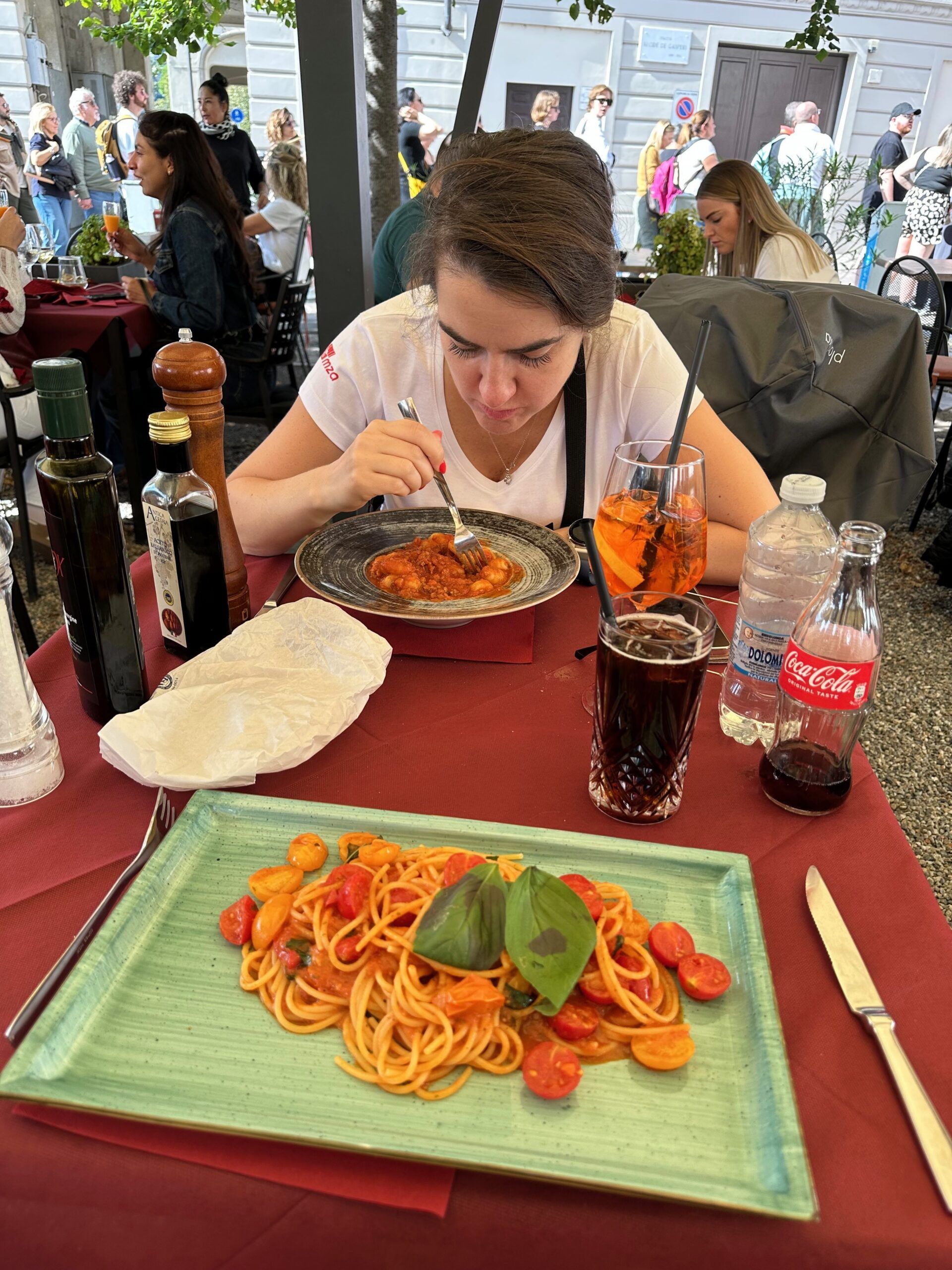 Kobieta je makaron w restauracji w milano foods, z daniem na pierwszym planie.