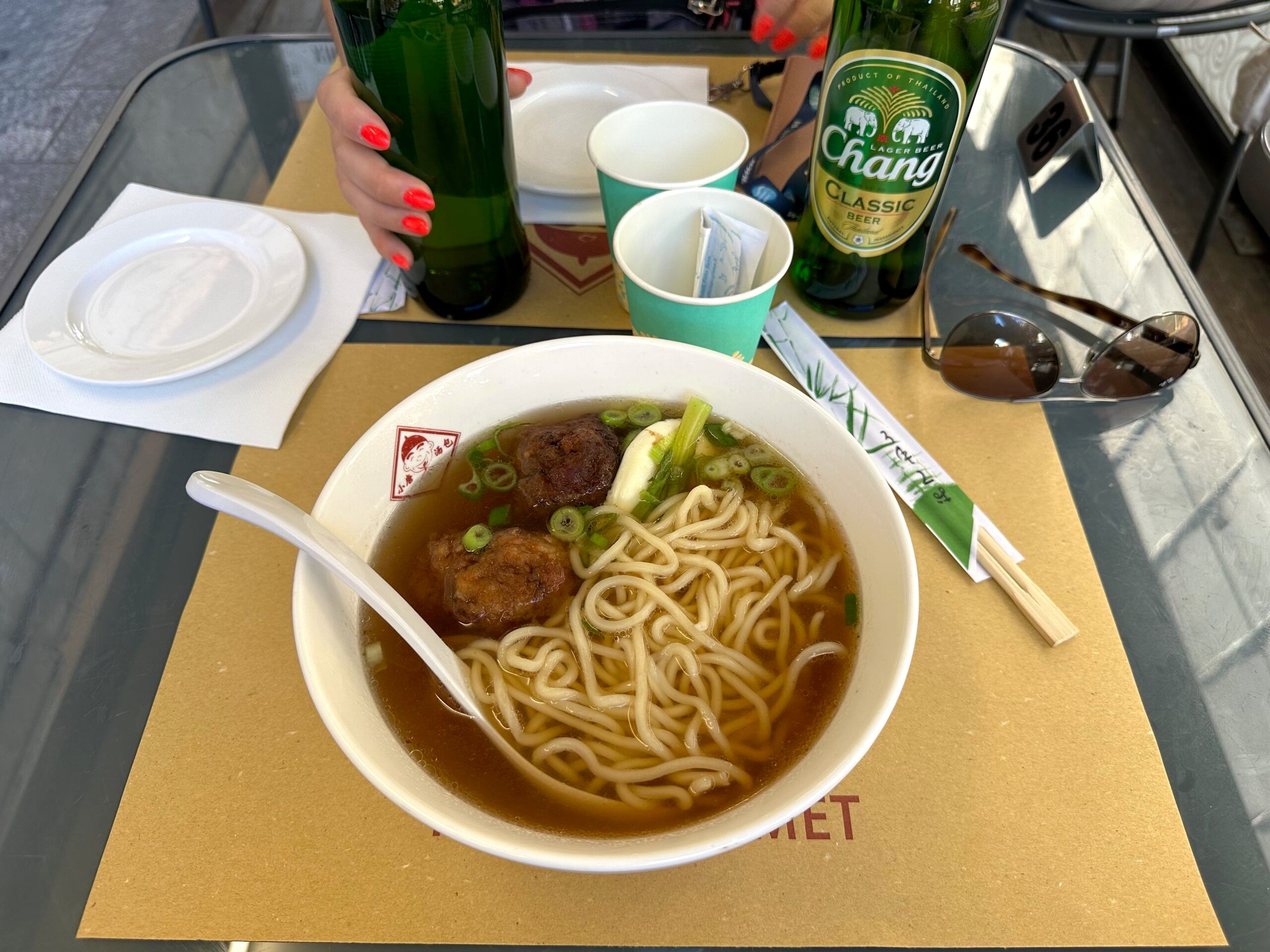 Makaronowa zupa z klopsikami w chinatown w mediolanie, z butelkami piwa na stole