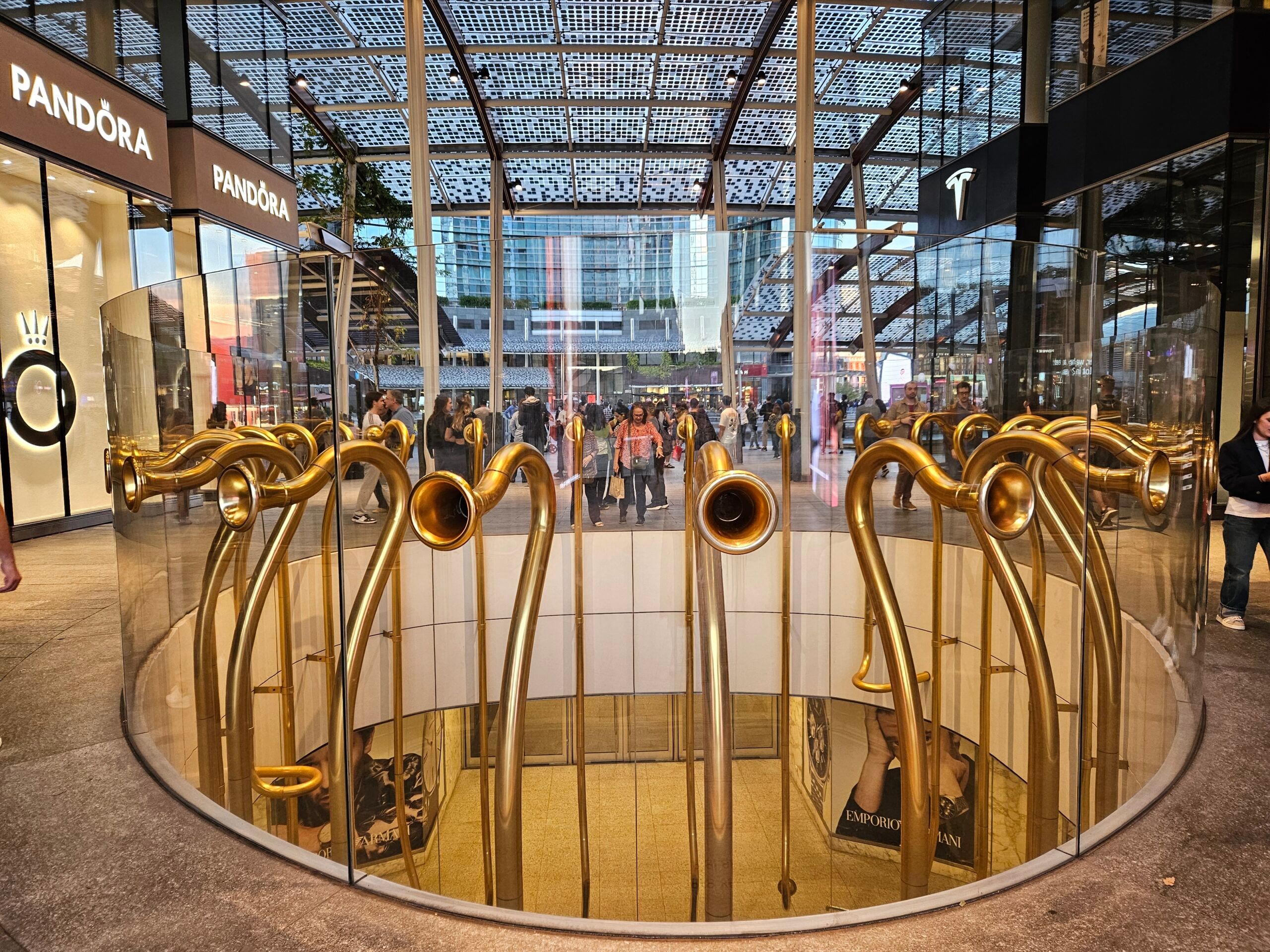 Piazza gae aulenti w mediolanie z nowoczesnym pawilonem i złotą instalacją w centrum.