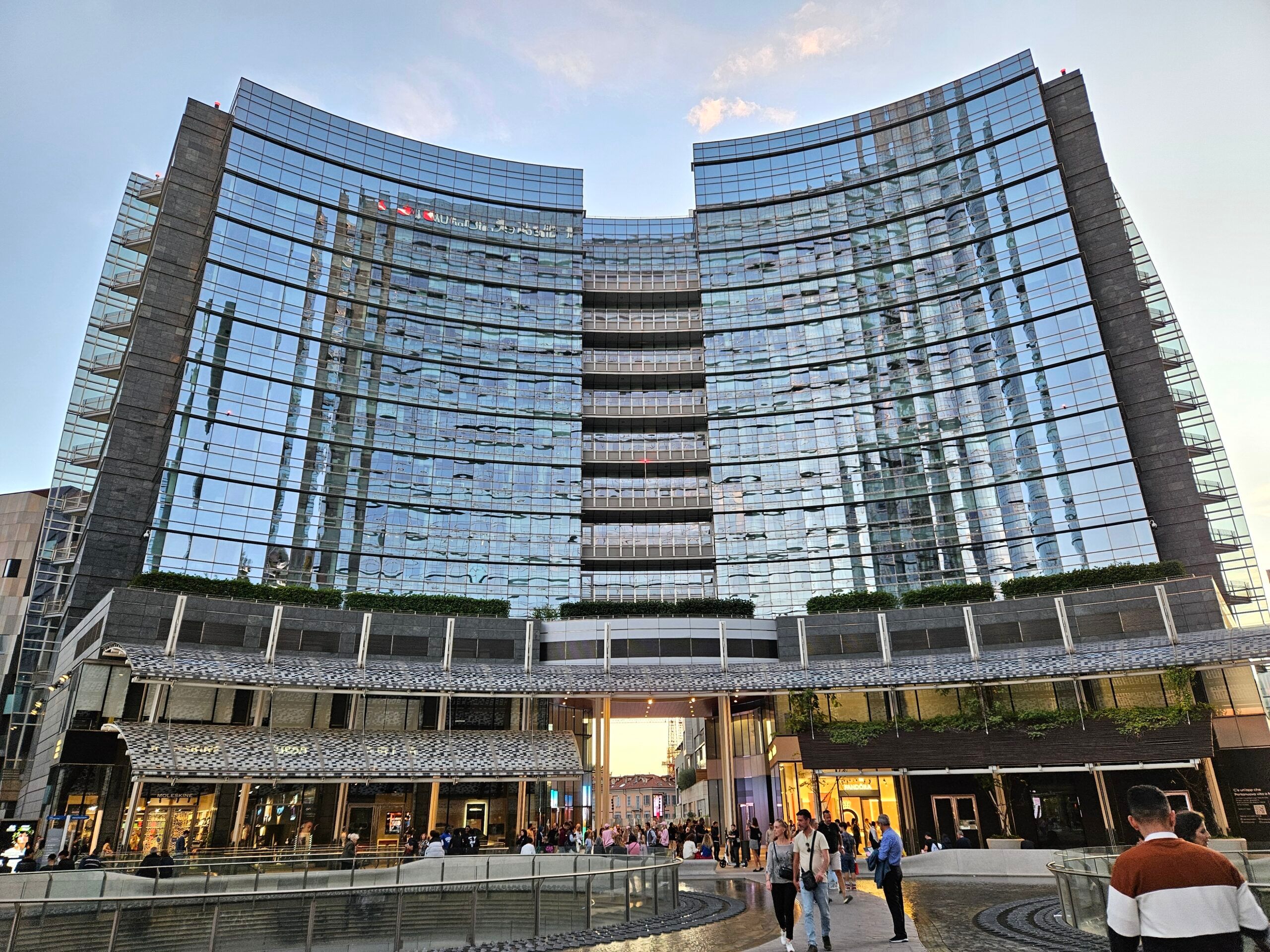 Piazza gae aulenti w mediolanie z nowoczesnym szklanym budynkiem i spacerującymi ludźmi