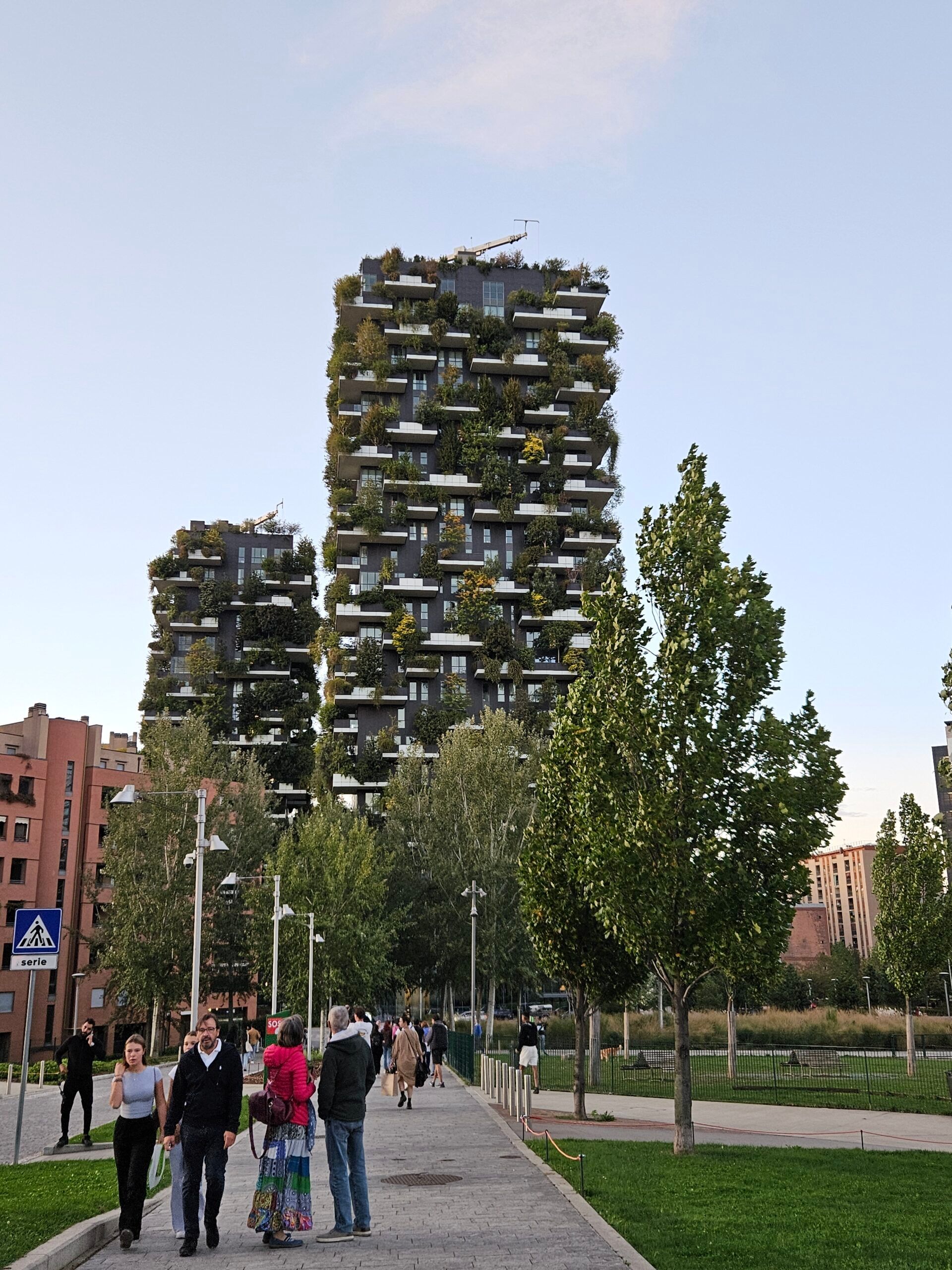 Bosco verticale w mediolanie z wieżami porośniętymi drzewami i spacerowiczami w parku