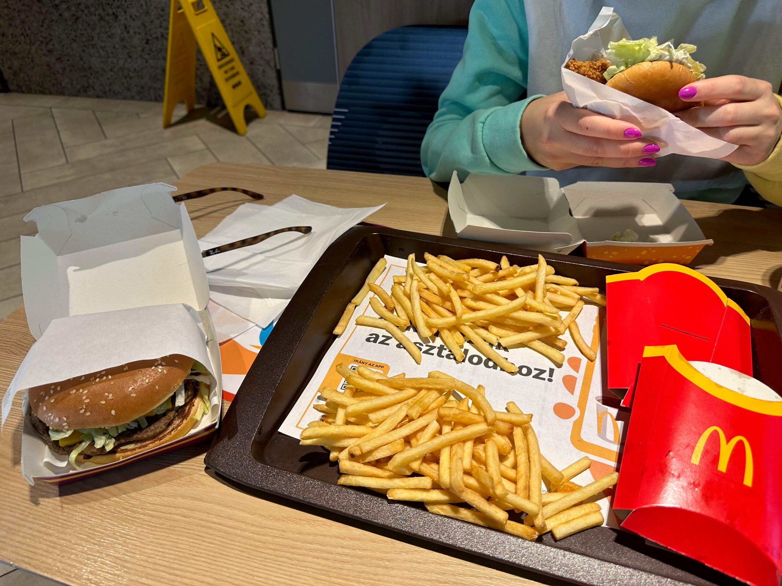 Posiłek w mcdonald’s w budapeszcie: burgery, frytki i napój na stole.