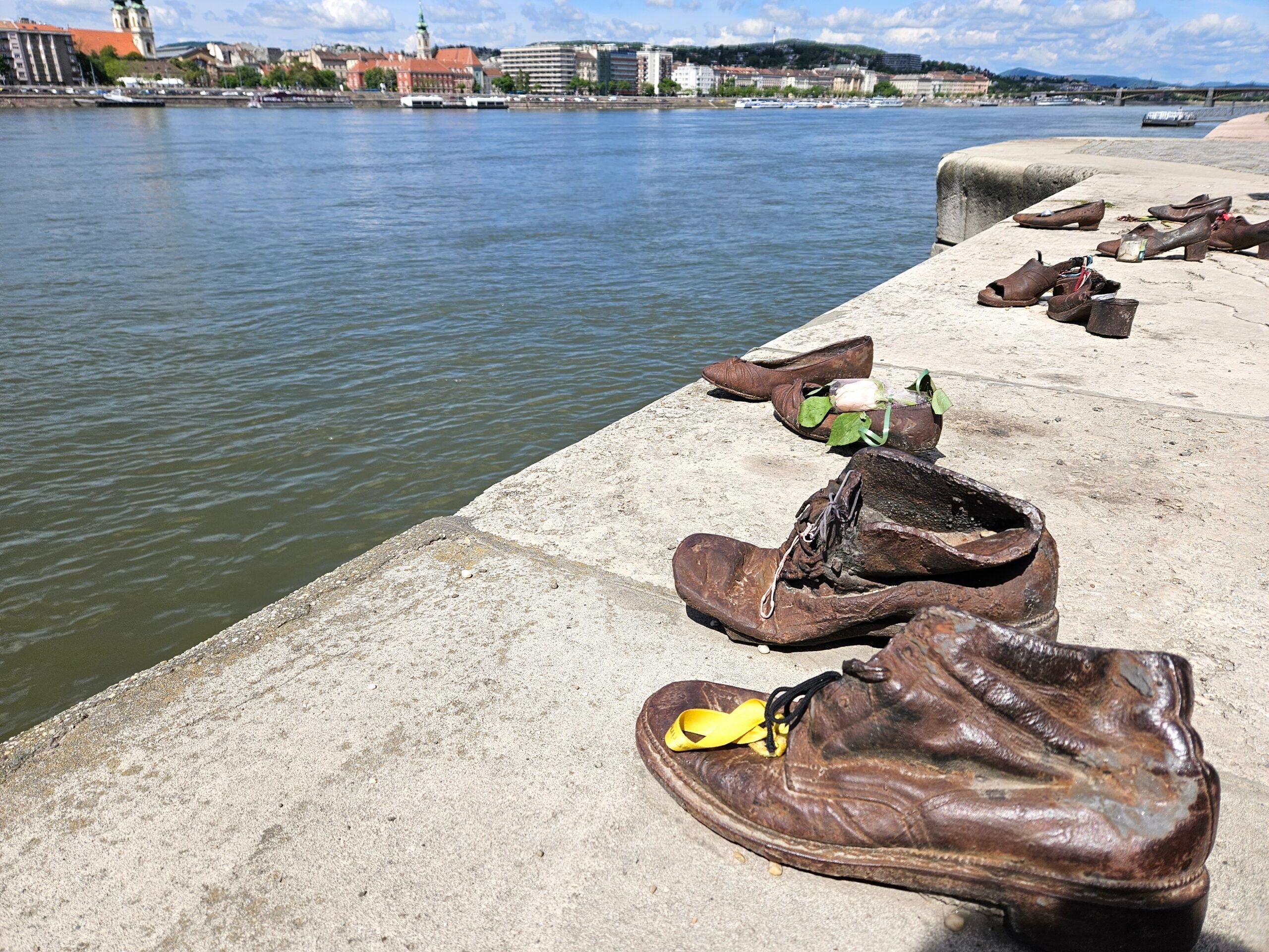 Pomnik buty na brzegu dunaju w budapeszcie, rząd metalowych butów na nabrzeżu rzeki.