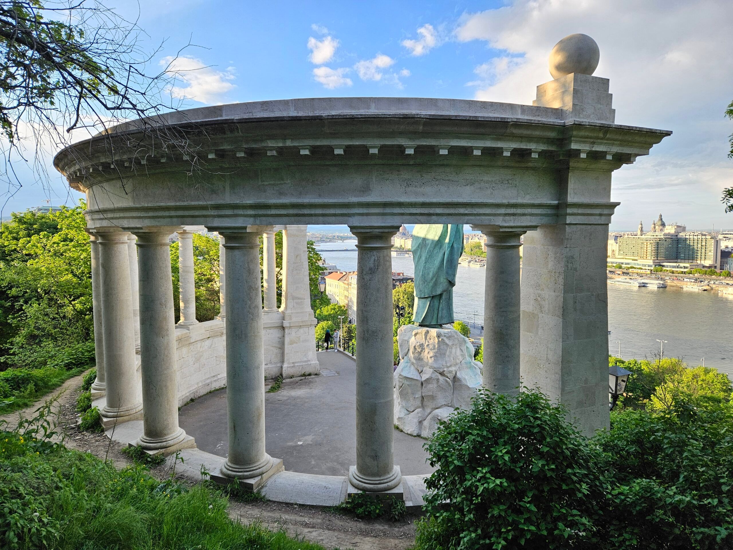 Pomnik na gellért hill w budapeszcie, z kolumnadą i widokiem na dunaj.