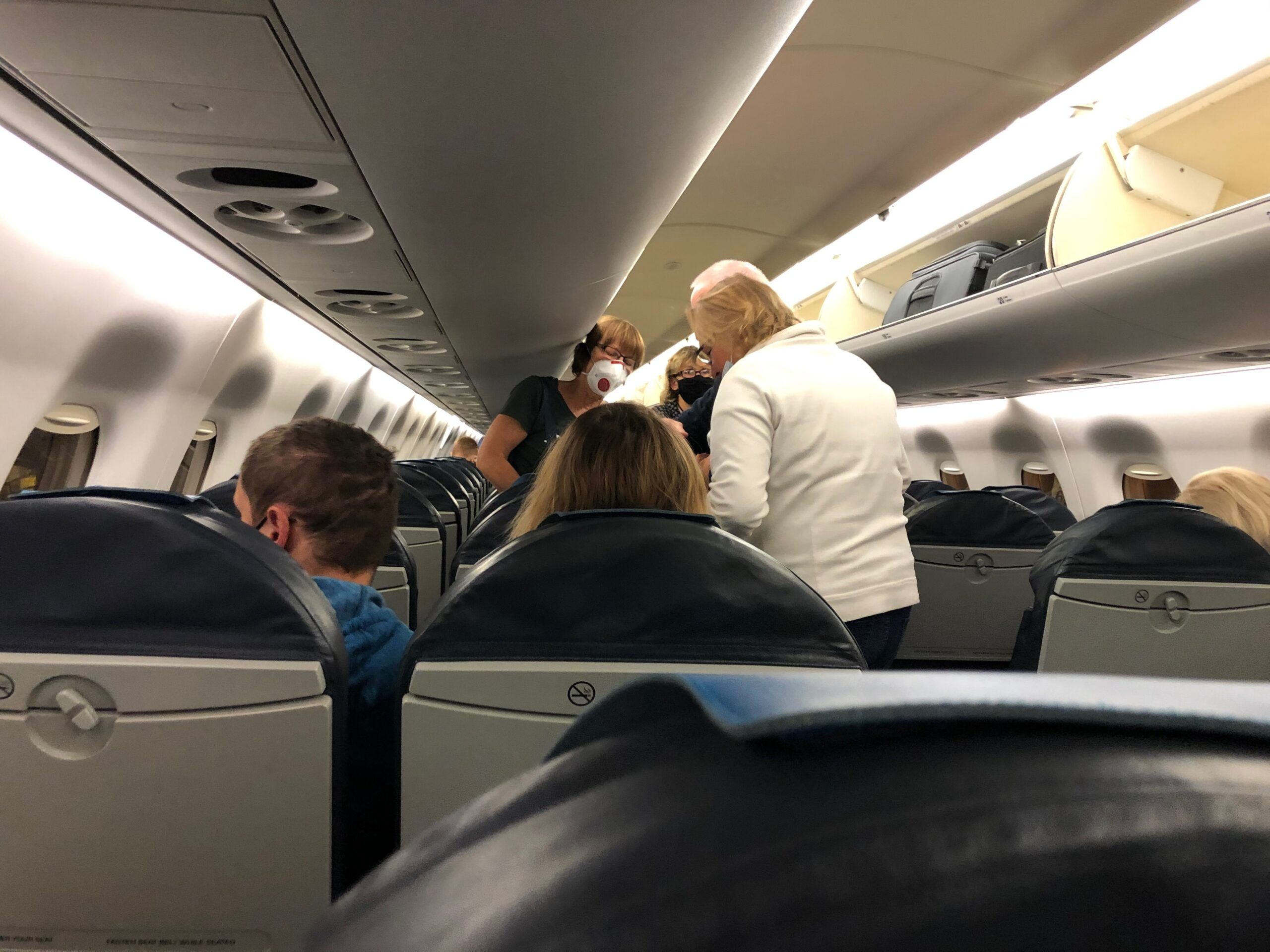 Wnętrze samolotu na amsterdam airport z pasażerami stojącymi w przejściu.