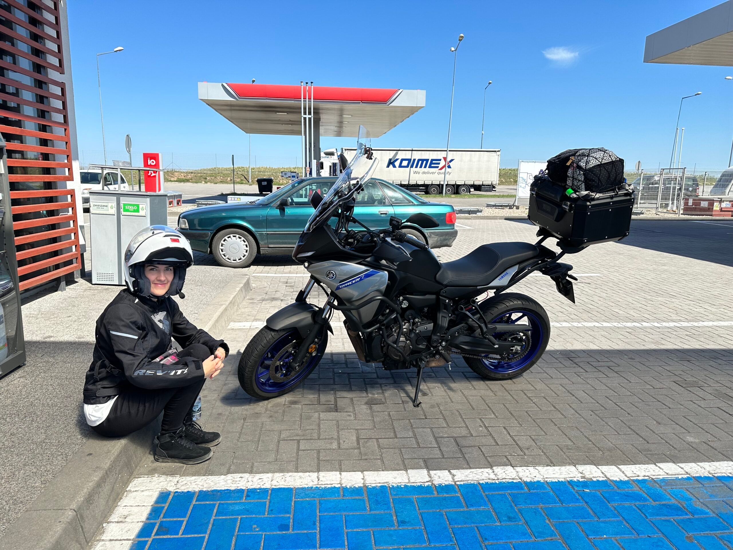 Motocyklistka siedzi przy zaparkowanym motocyklu yamaha tracer na stacji paliw w szczecinie.