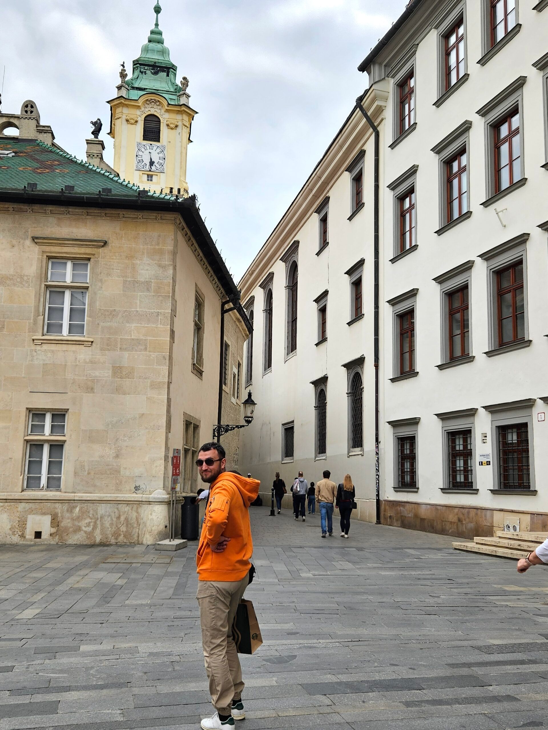 Historyczne uliczki starego miasta w bratysławie z wieżą zegarową.