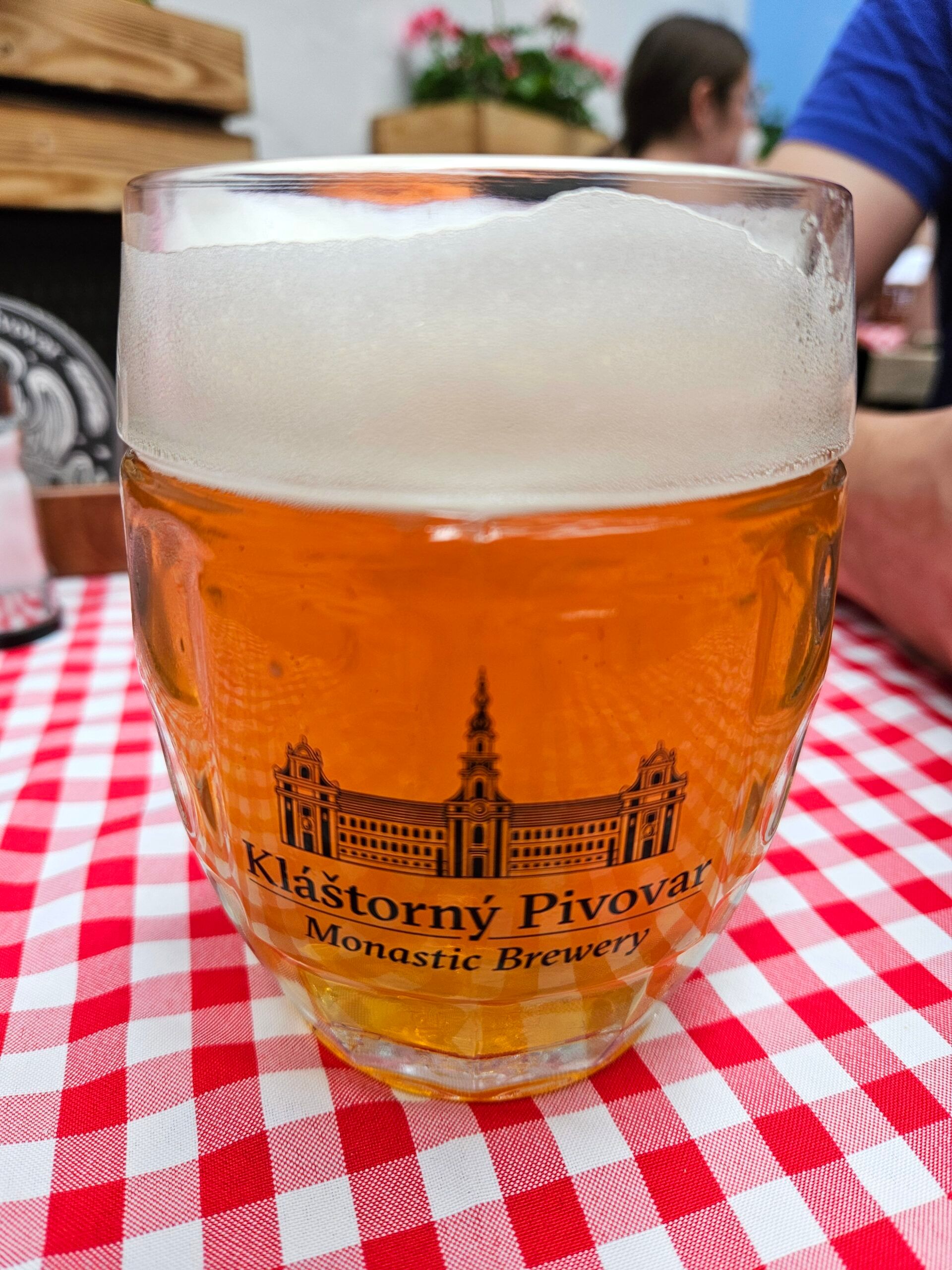 Szklanka piwa z logo kláštorndy pivovar na czerwono-białym obrusie w bratysławie