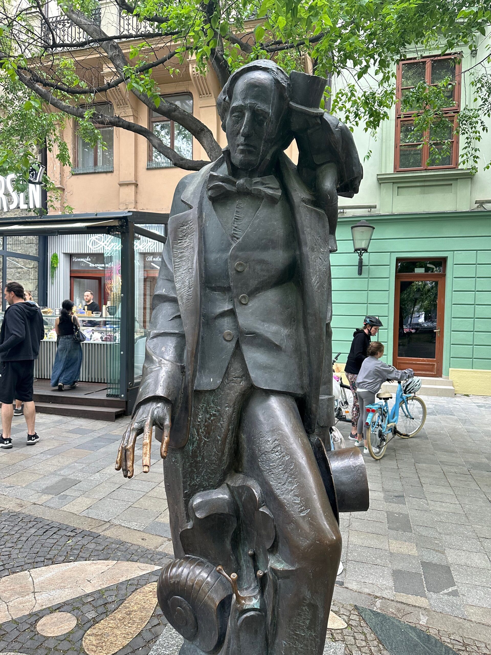 Pomnik na ulicy w bratysławie przedstawiający eleganckiego mężczyznę z walizką.