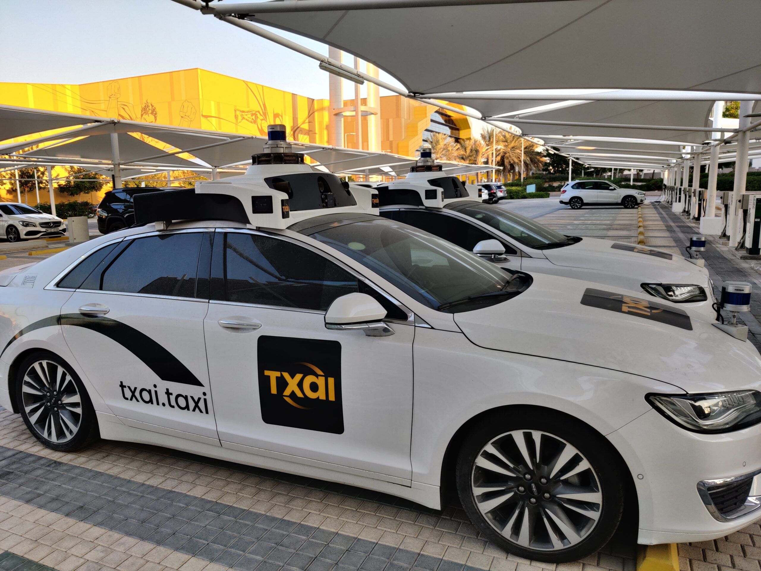 Autonomiczne taksówki txai w abu zabi, zaparkowane pod zadaszeniem.