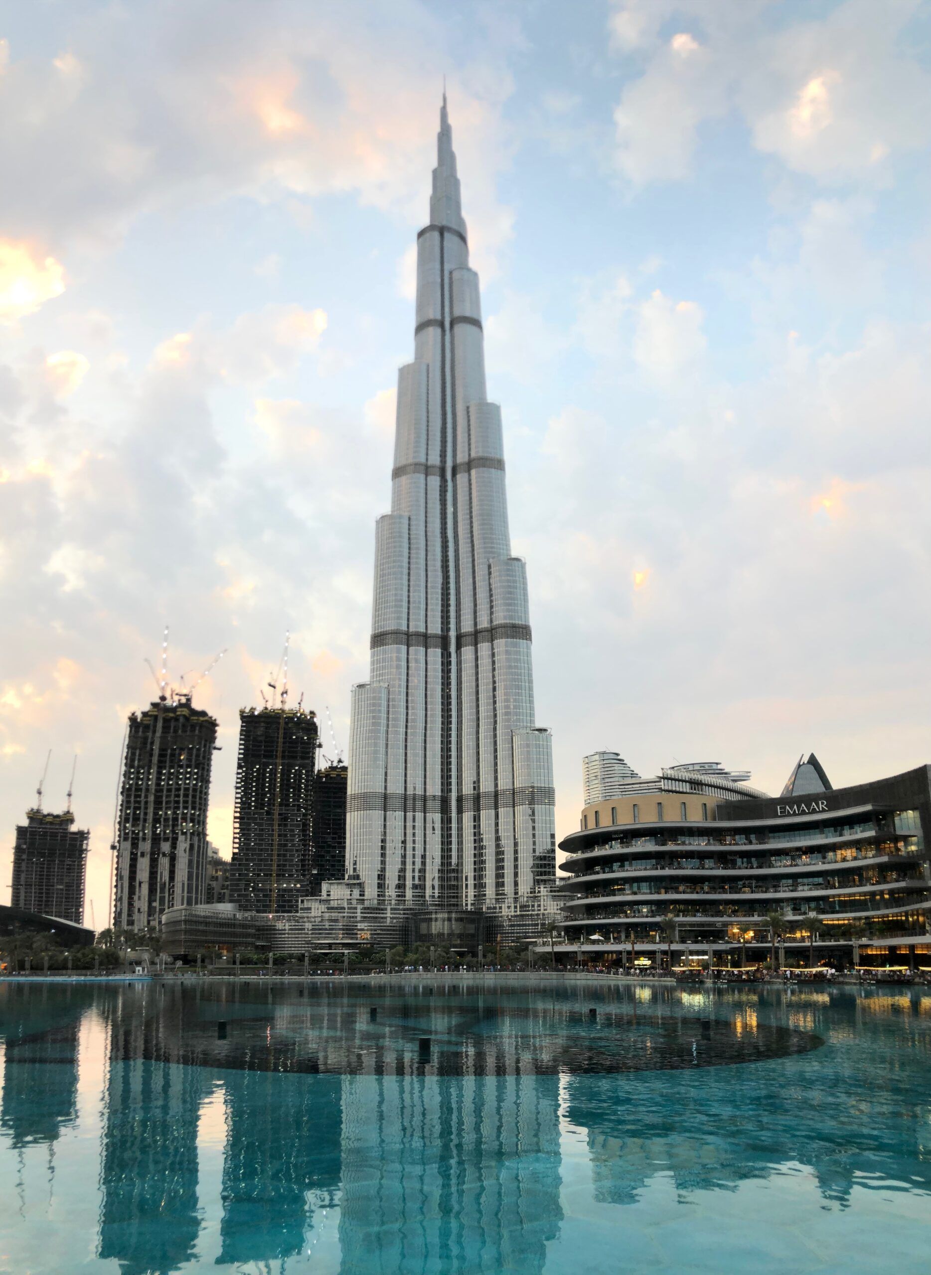 Burj khalifa w dubaju odbijający się w fontannie o zachodzie słońca