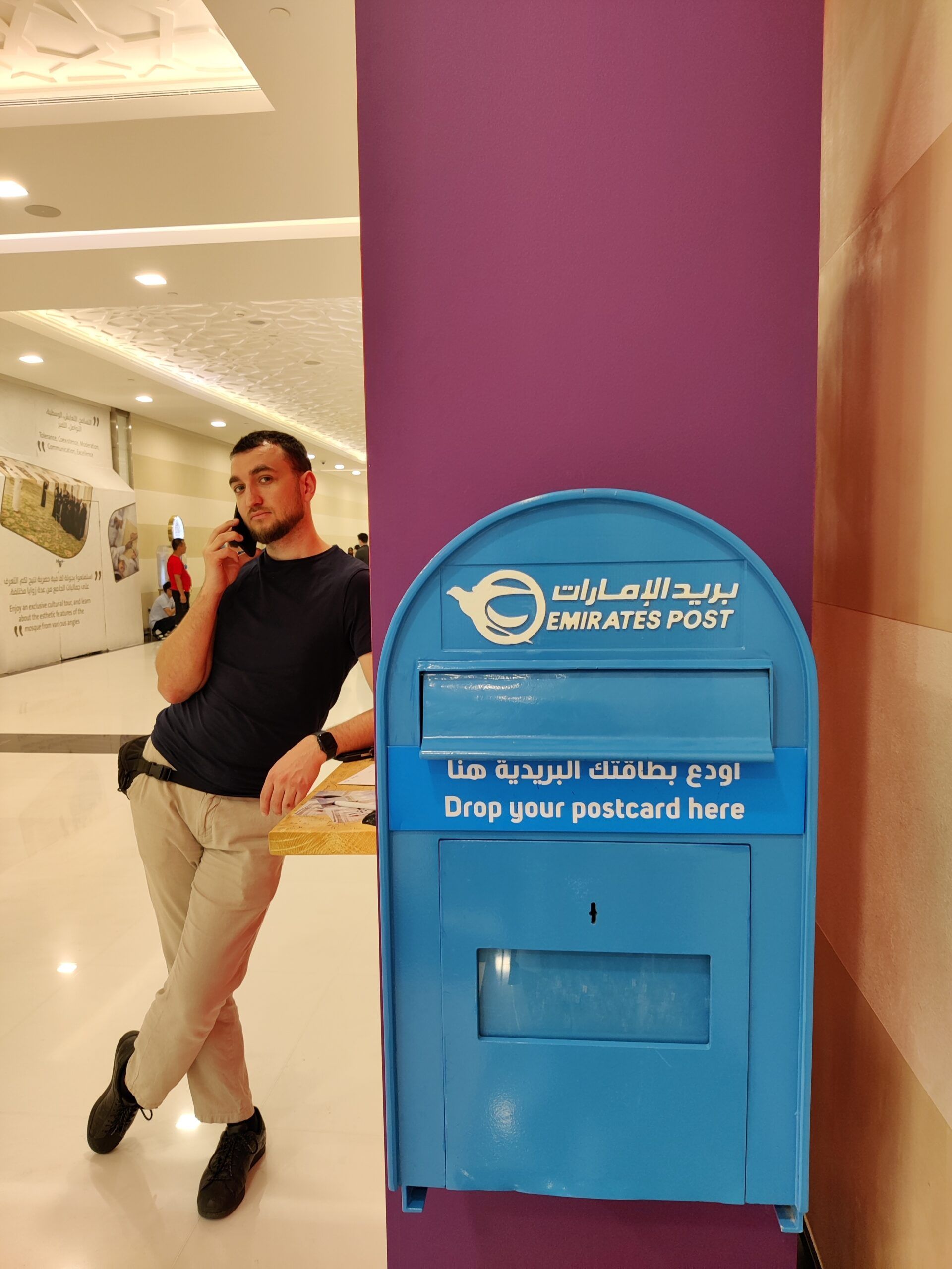 Mężczyzna opiera się przy niebieskiej skrzynce emirates post w abu zabi.