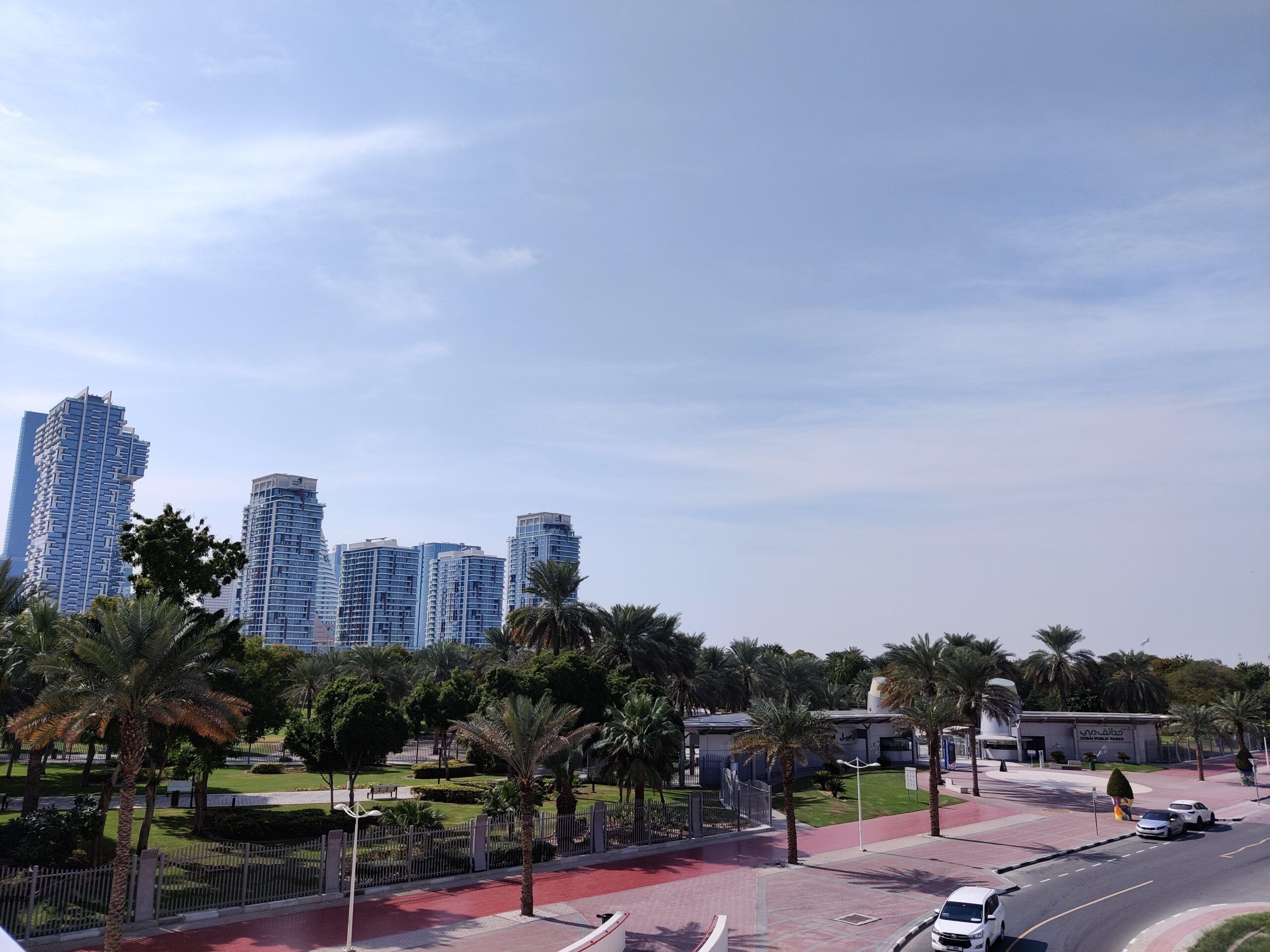 Panorama dubaju z wieżowcami, palmami i parkiem przy drodze