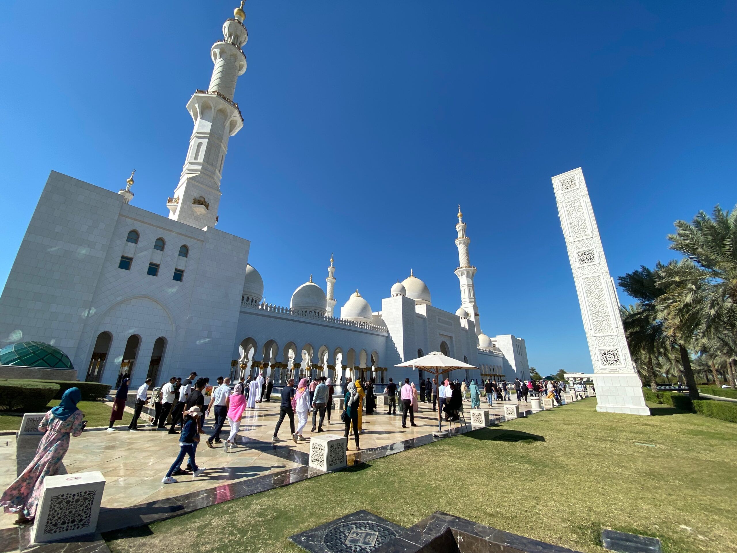 Wielki biały meczet w abu zabi z minaretami i zwiedzającymi na dziedzińcu