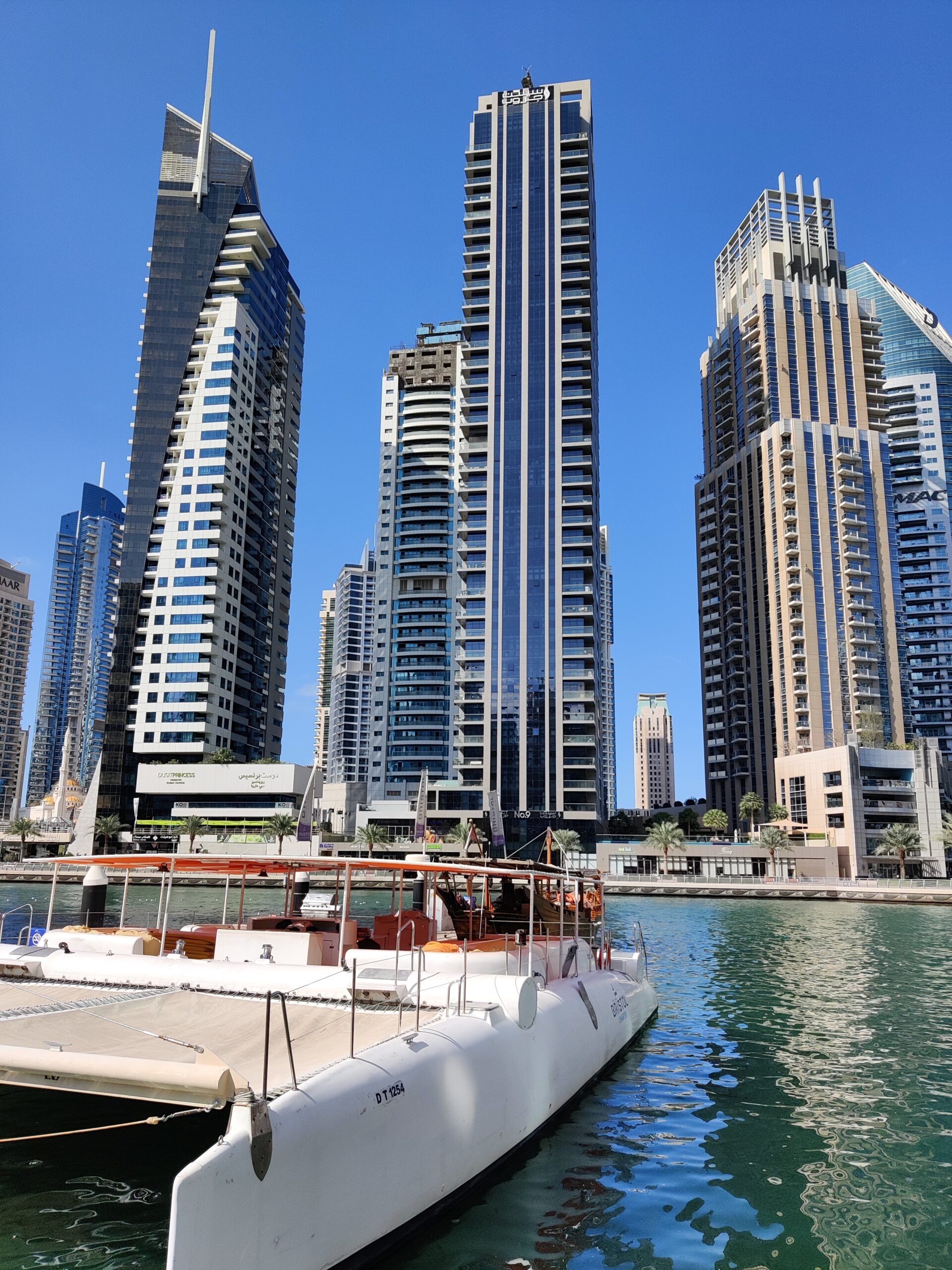 Dubaj marina z wysokimi wieżowcami i zacumowaną białą łodzią