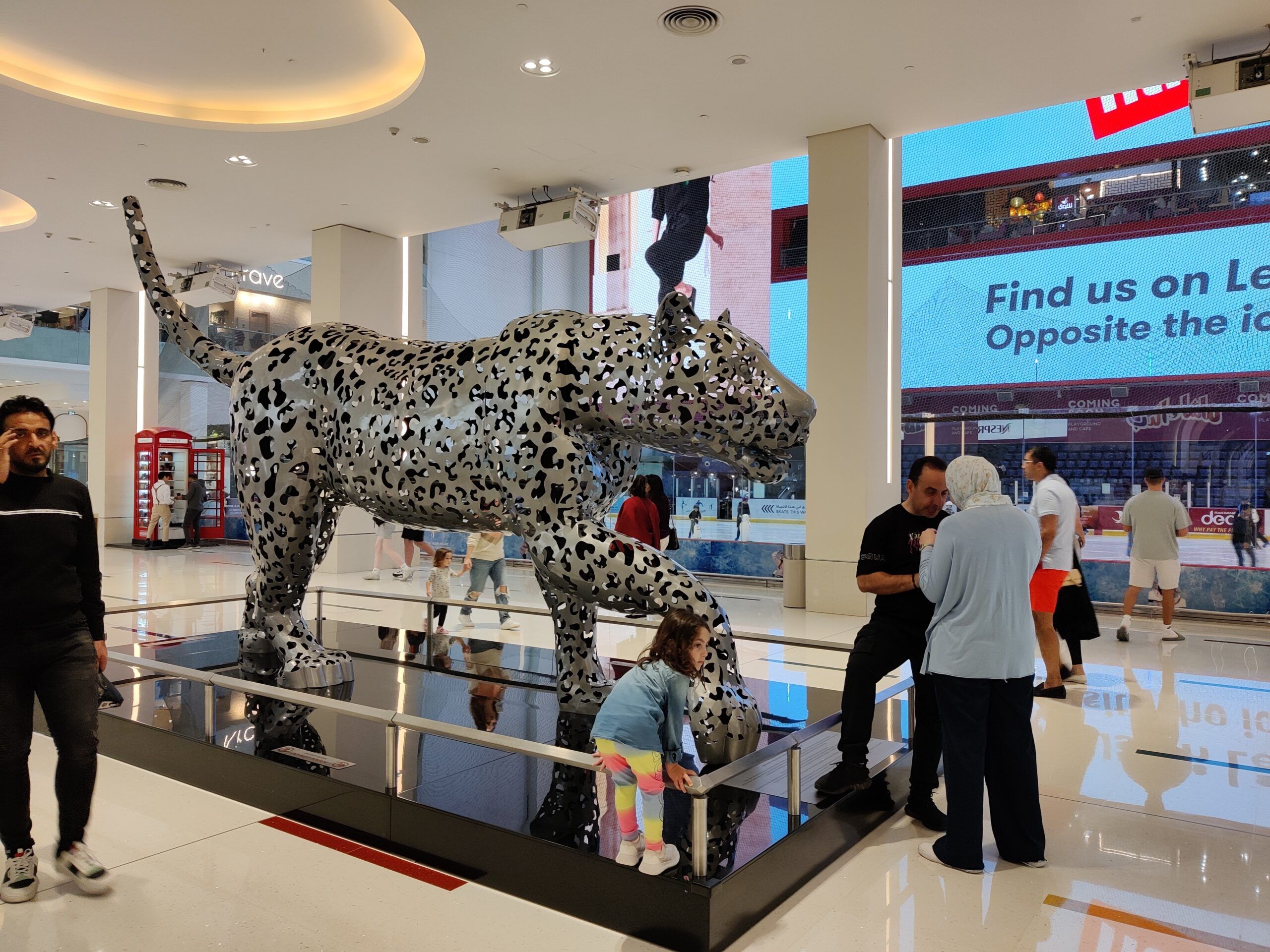 Rzeźba lamparta w dubai mall, otoczona spacerującymi ludźmi.