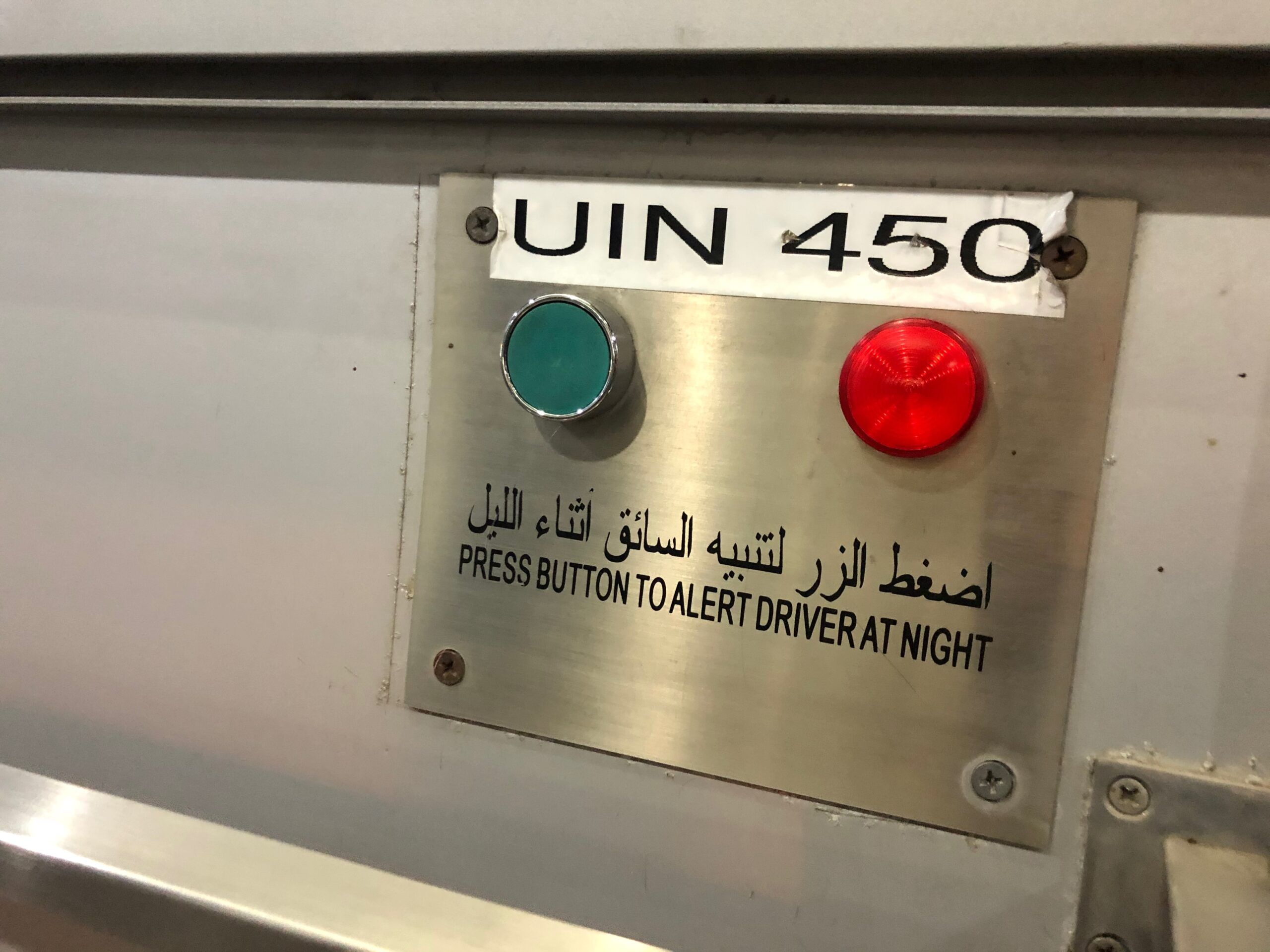 Panel z przyciskami w dubajskim środku transportu, z napisem o ostrzeganiu kierowcy w nocy.