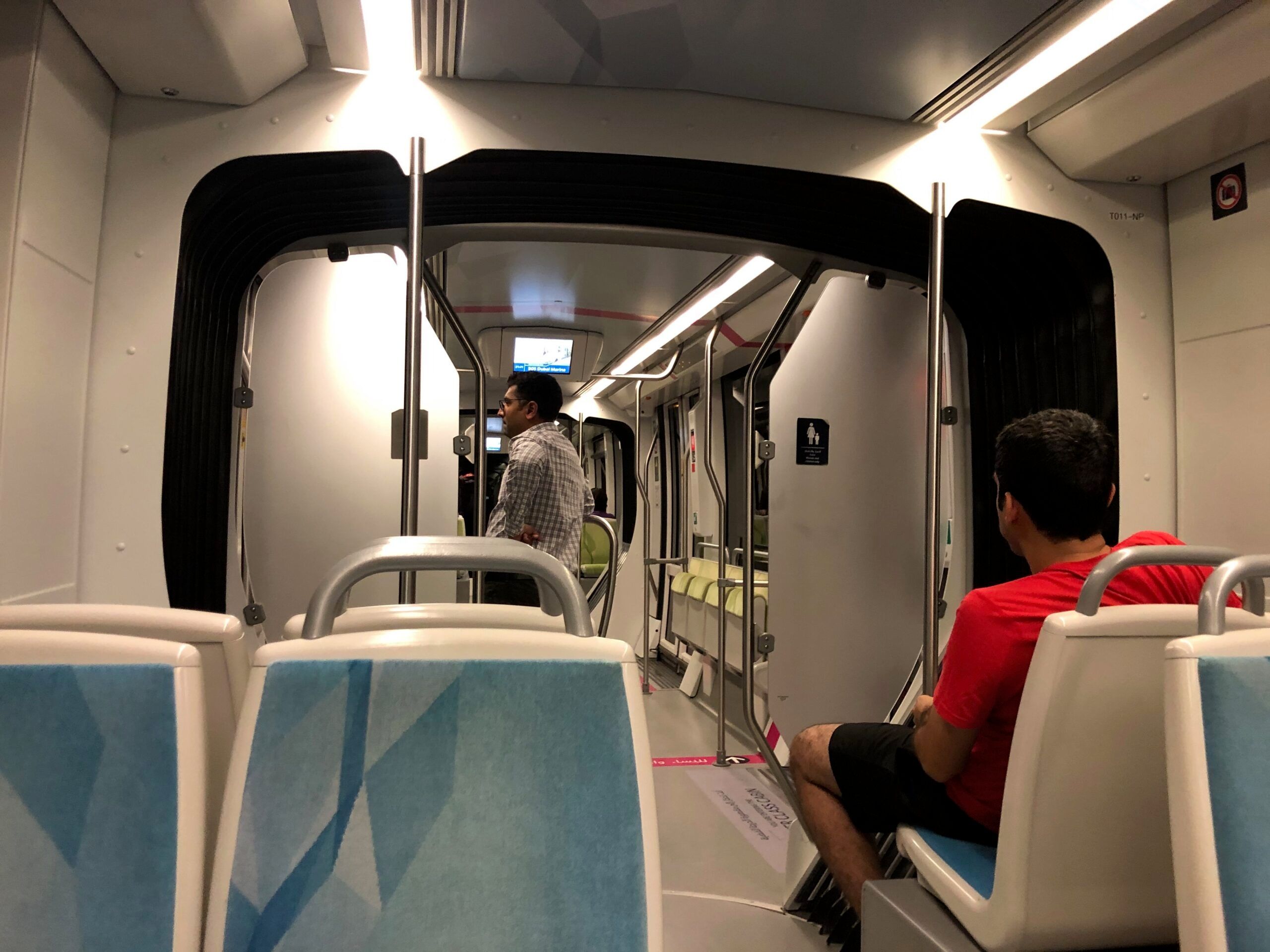 Wnętrze dubai tram w dubaju z pasażerami siedzącymi i stojącymi.