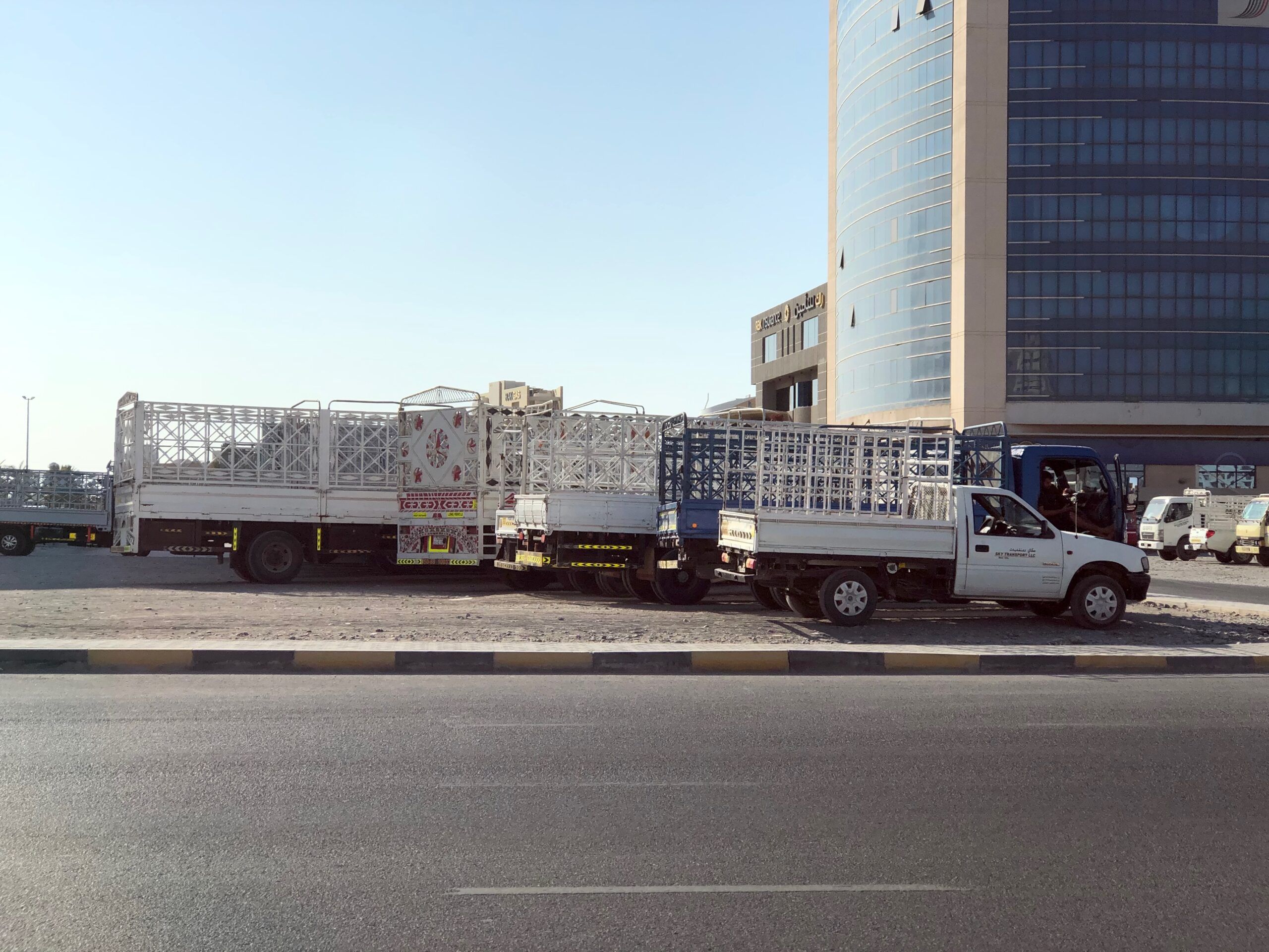 Droga w ras al khaimah z zaparkowanymi ciężarówkami i wieżowcem w tle