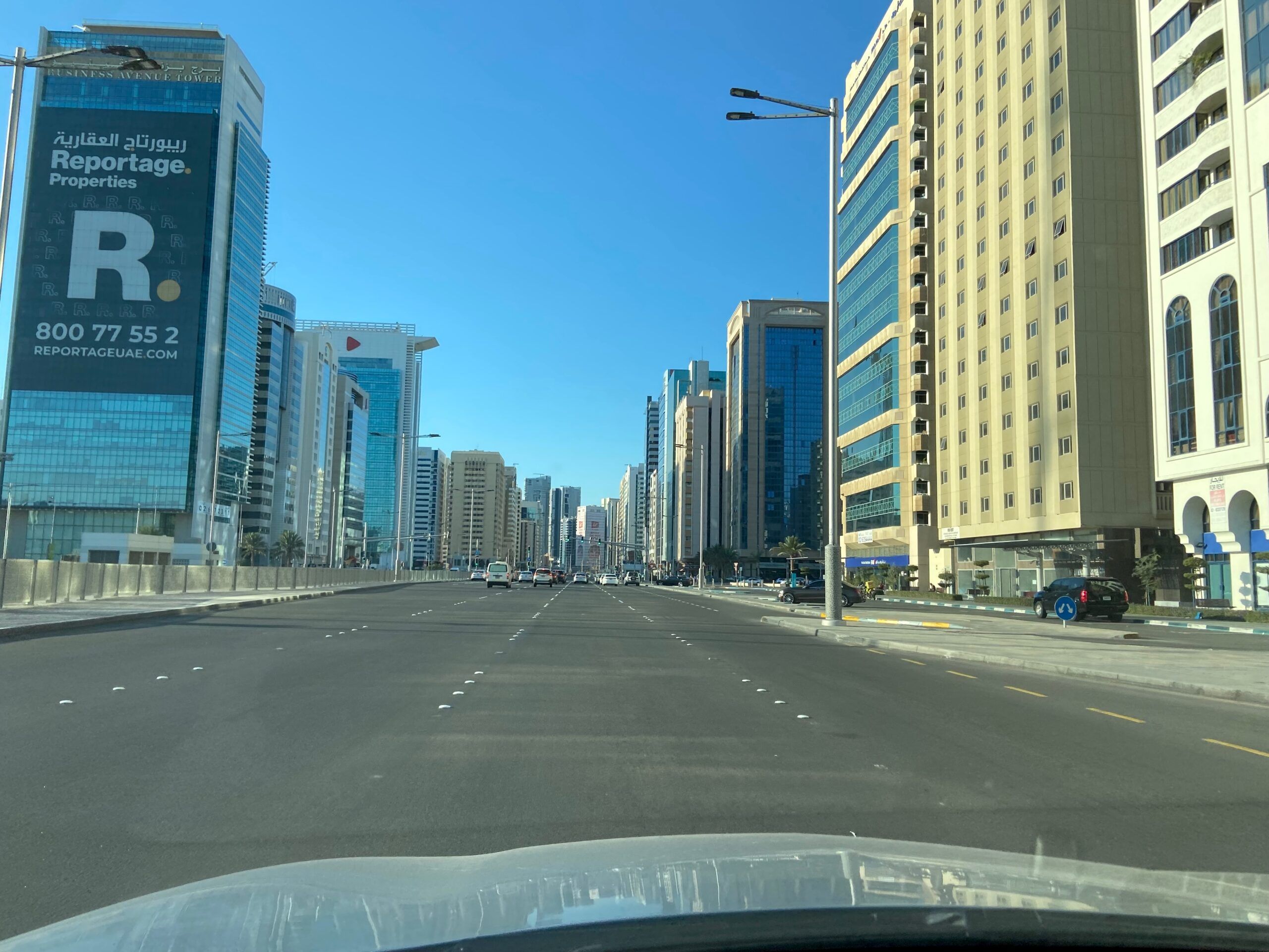 Szeroka droga w abu zabi z wieżowcami przy abu dhabi roads i bezchmurnym niebem.