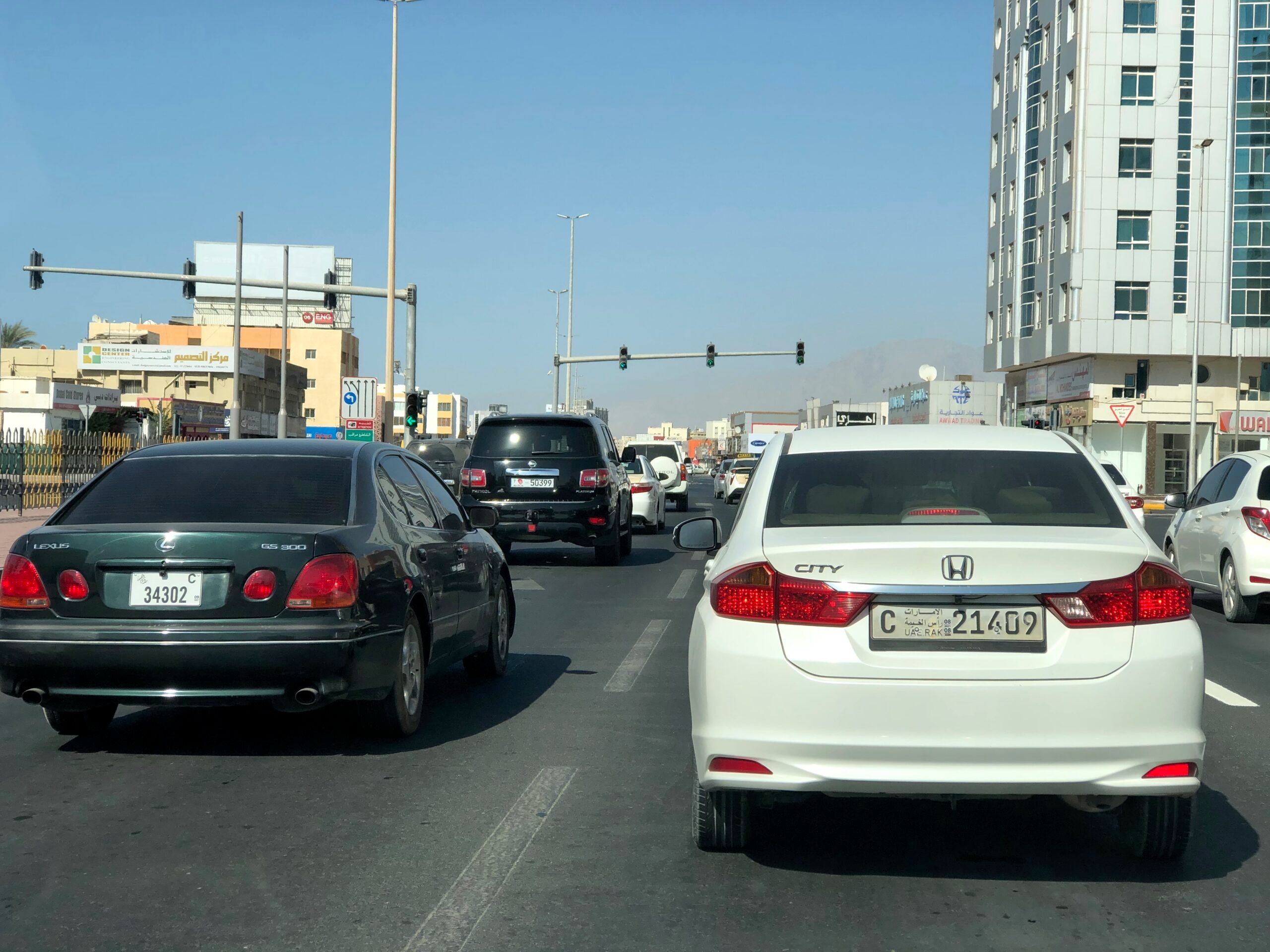 Ulica w ras al khaimah z ruchem samochodowym i wysokimi budynkami po obu stronach.