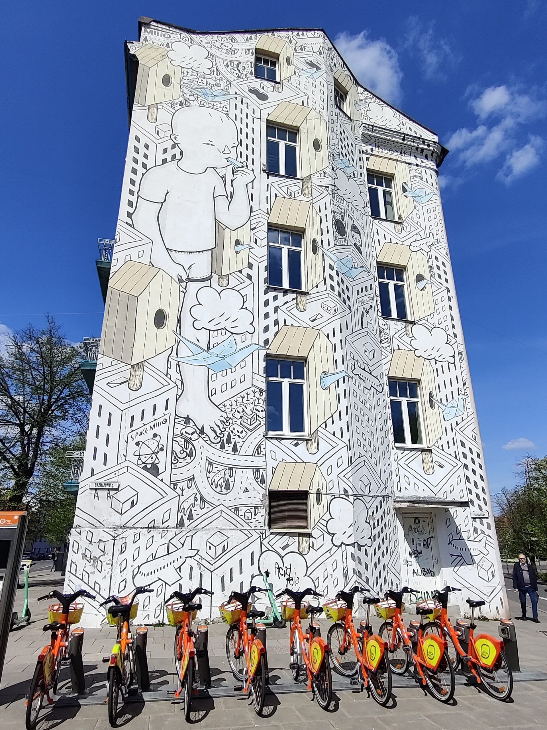 Mural na kamienicy w wilnie z rowerami miejskimi na pierwszym planie