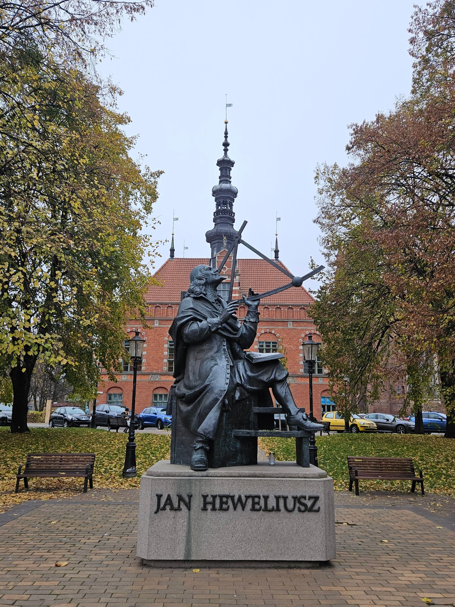 Pomnik jana heweliusza w gdańsku, z historycznym budynkiem w tle