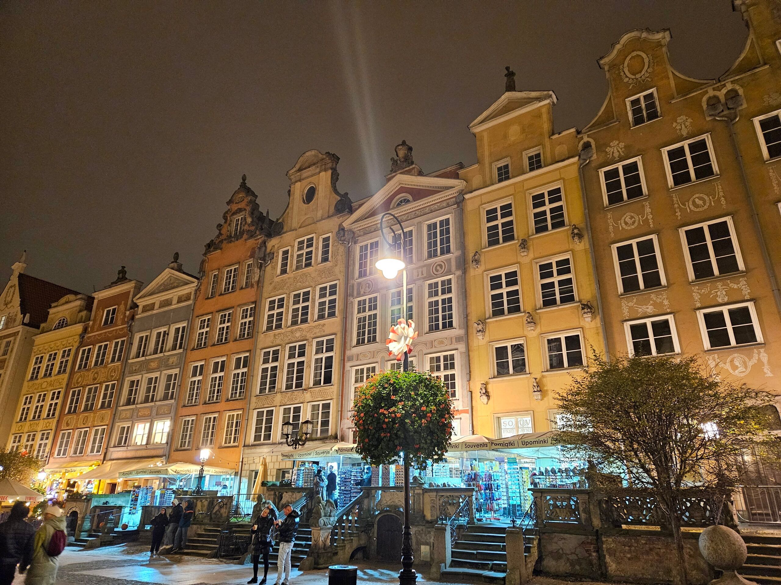 Stare miasto w gdańsku nocą z kolorowymi kamienicami i latarnią na placu.