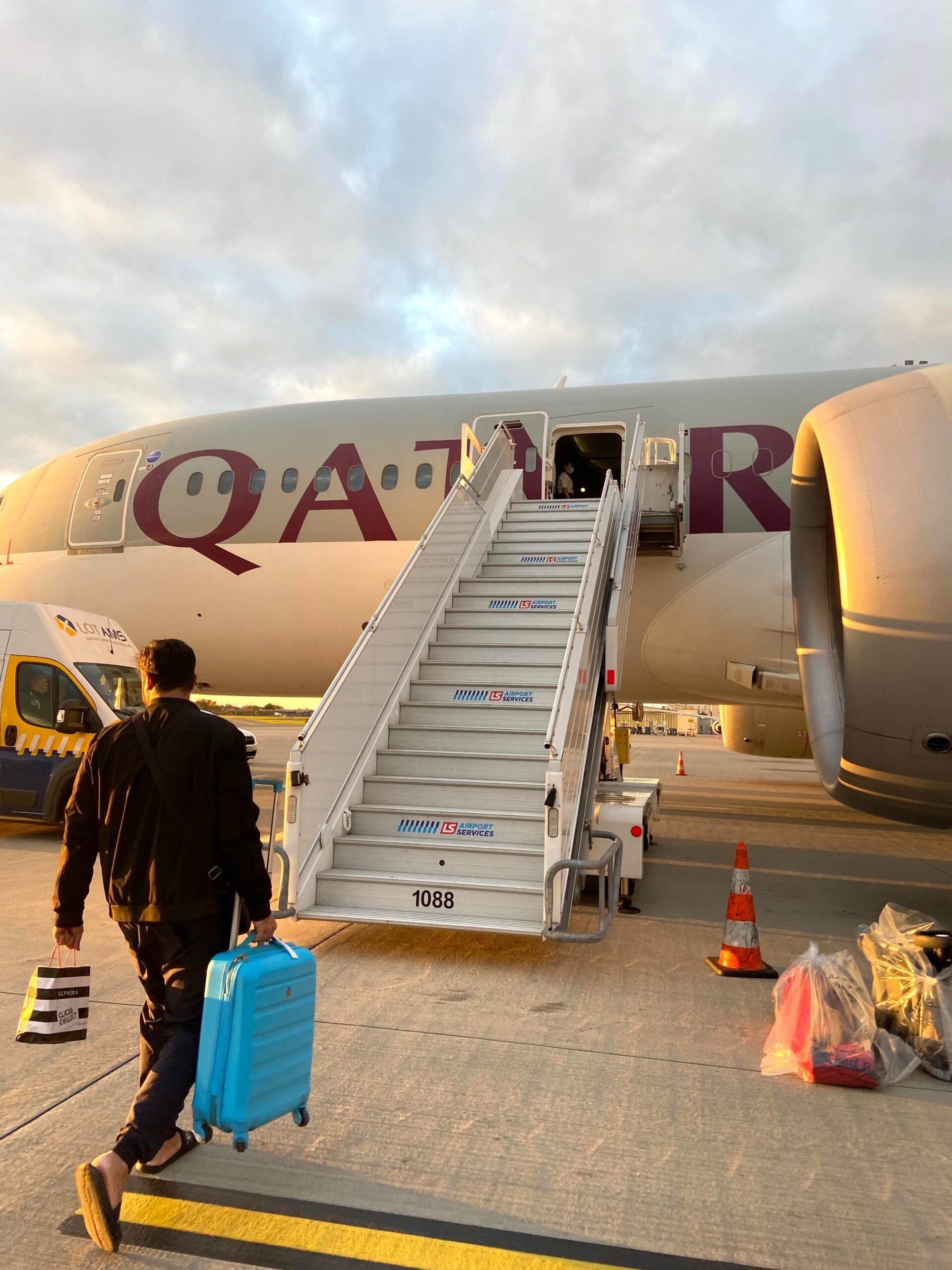 Pasażer idzie po schodach do samolotu qatar airways na lotnisku chopina w warszawie.