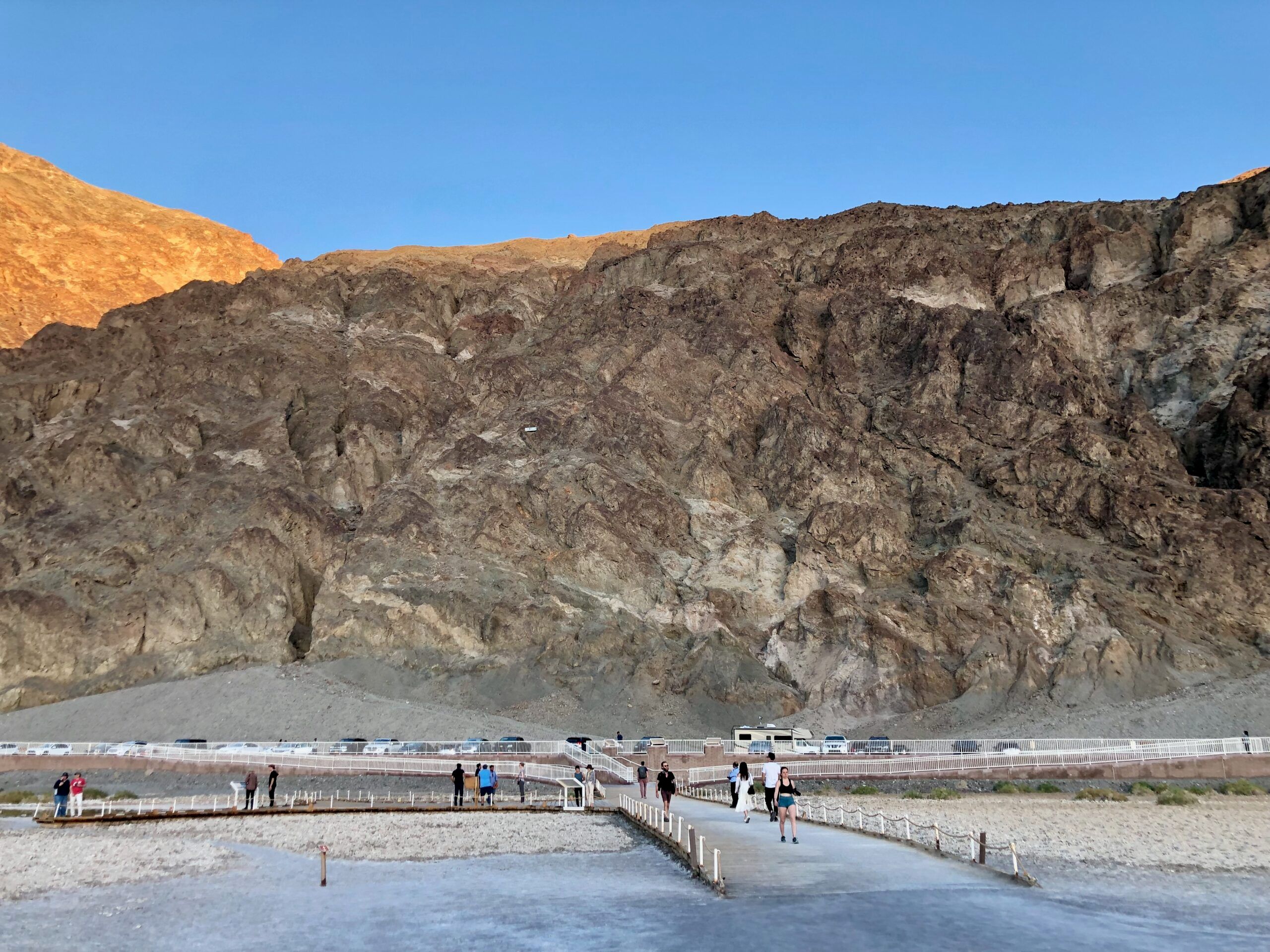 Death valley w usa o zachodzie słońca, z pomostem i turystami u stóp skalistego zbocza