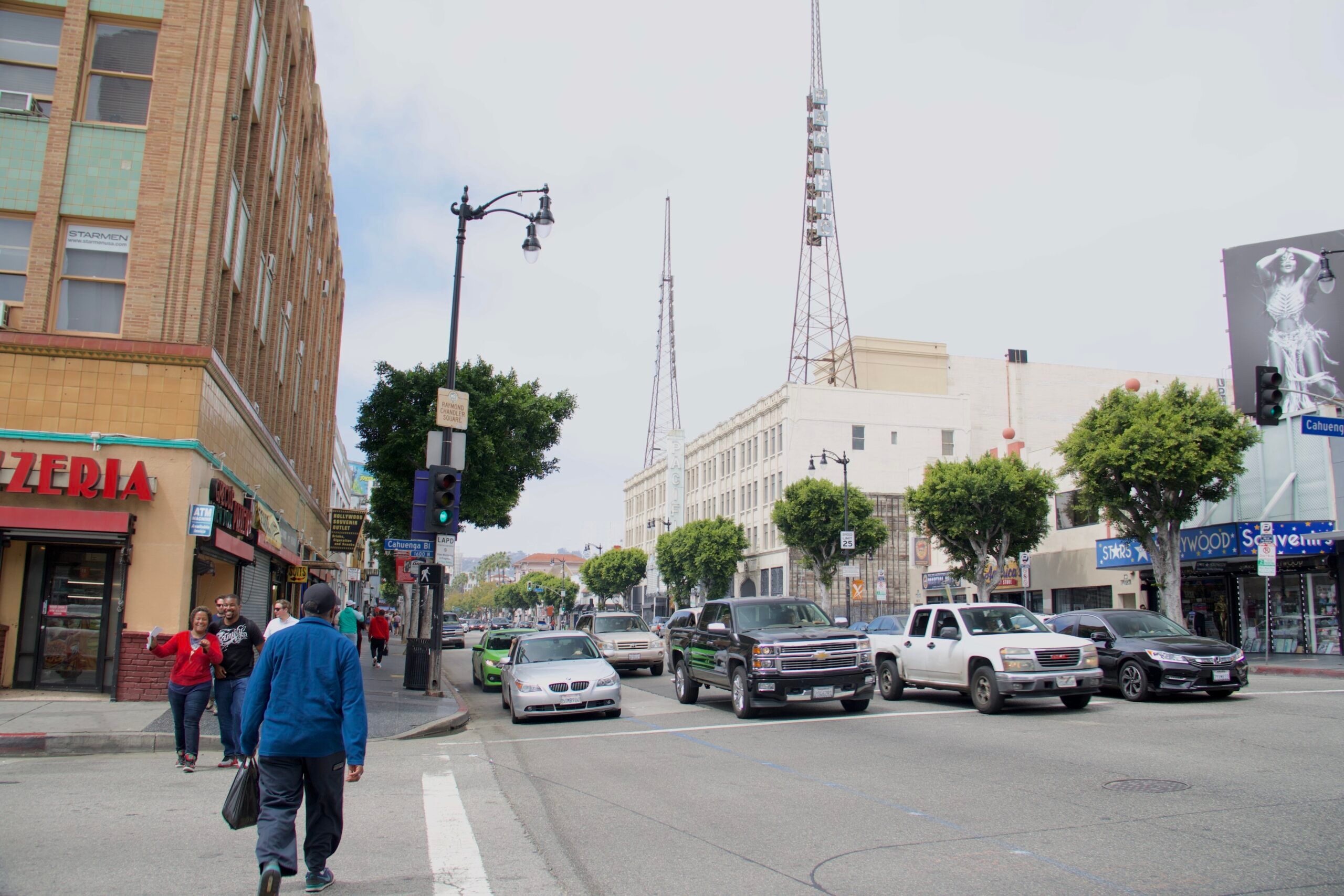 Ulica w los angeles z ruchem samochodowym, pieszymi i charakterystycznymi wieżami nad budynkami