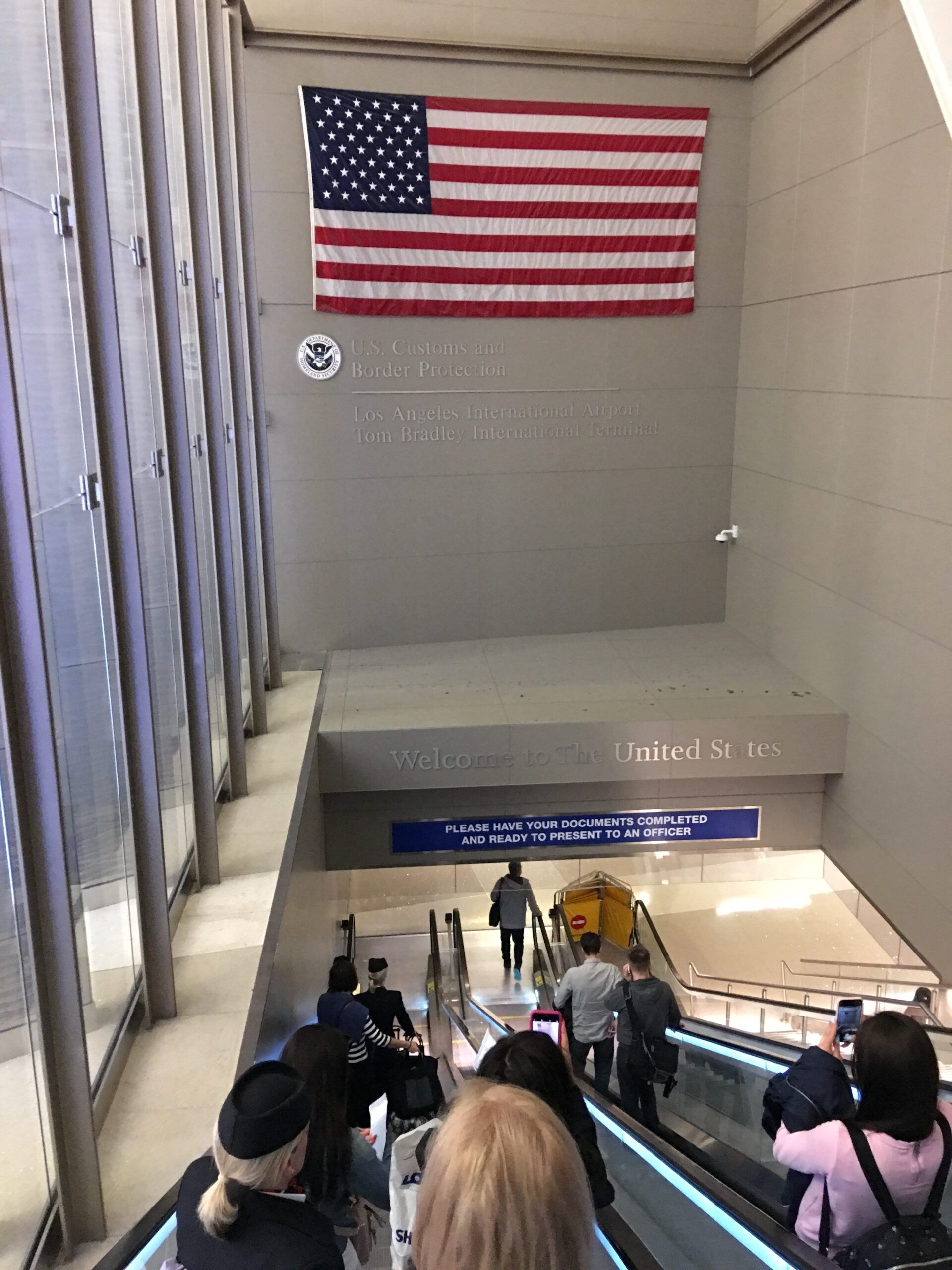 Kontrola paszportowa na lotnisku los angeles international airport z flagą usa i ruchomymi schodami.