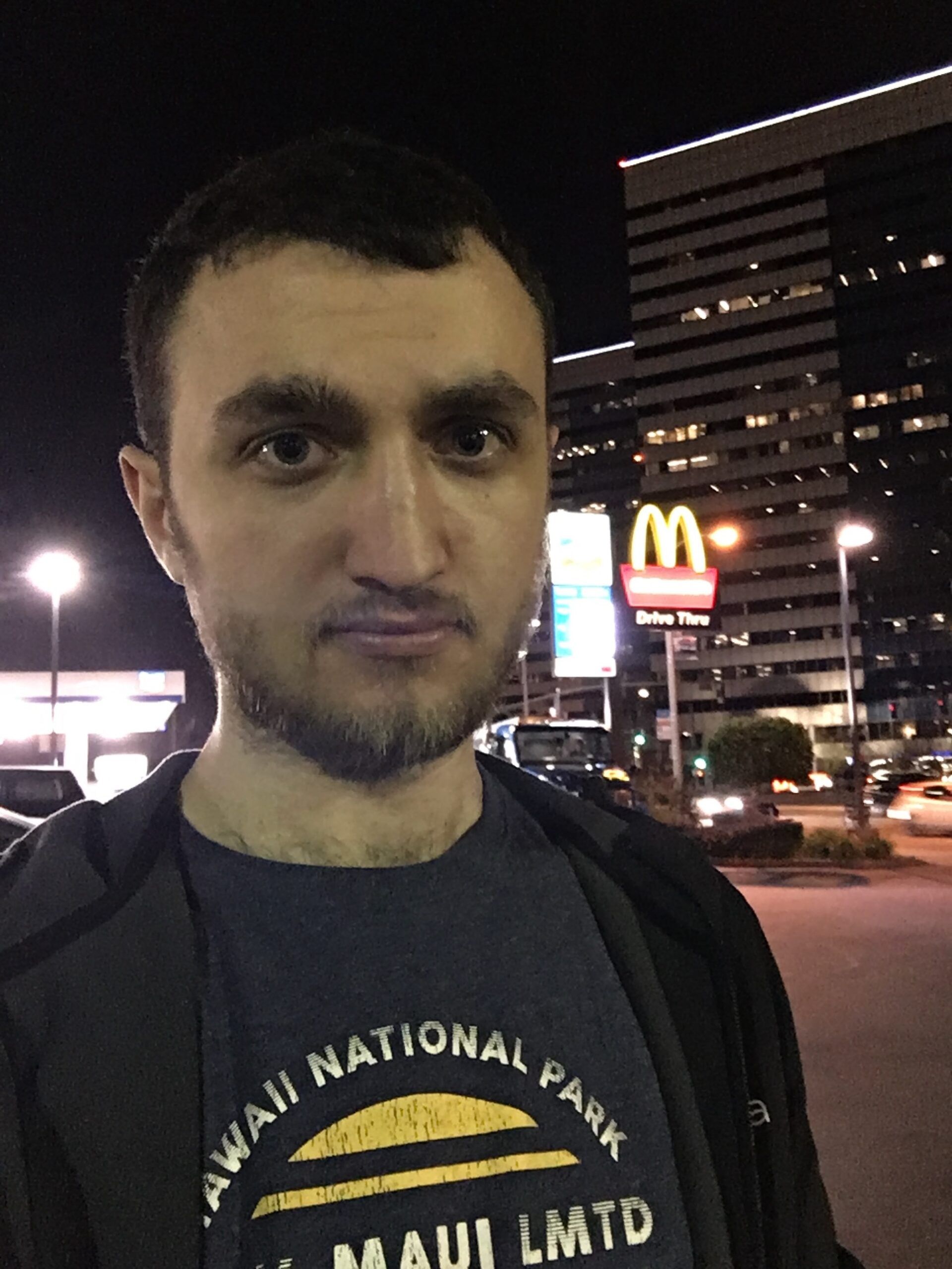 Mężczyzna na nocnej ulicy w los angeles z neonem mcdonald’s i wieżowcem w tle
