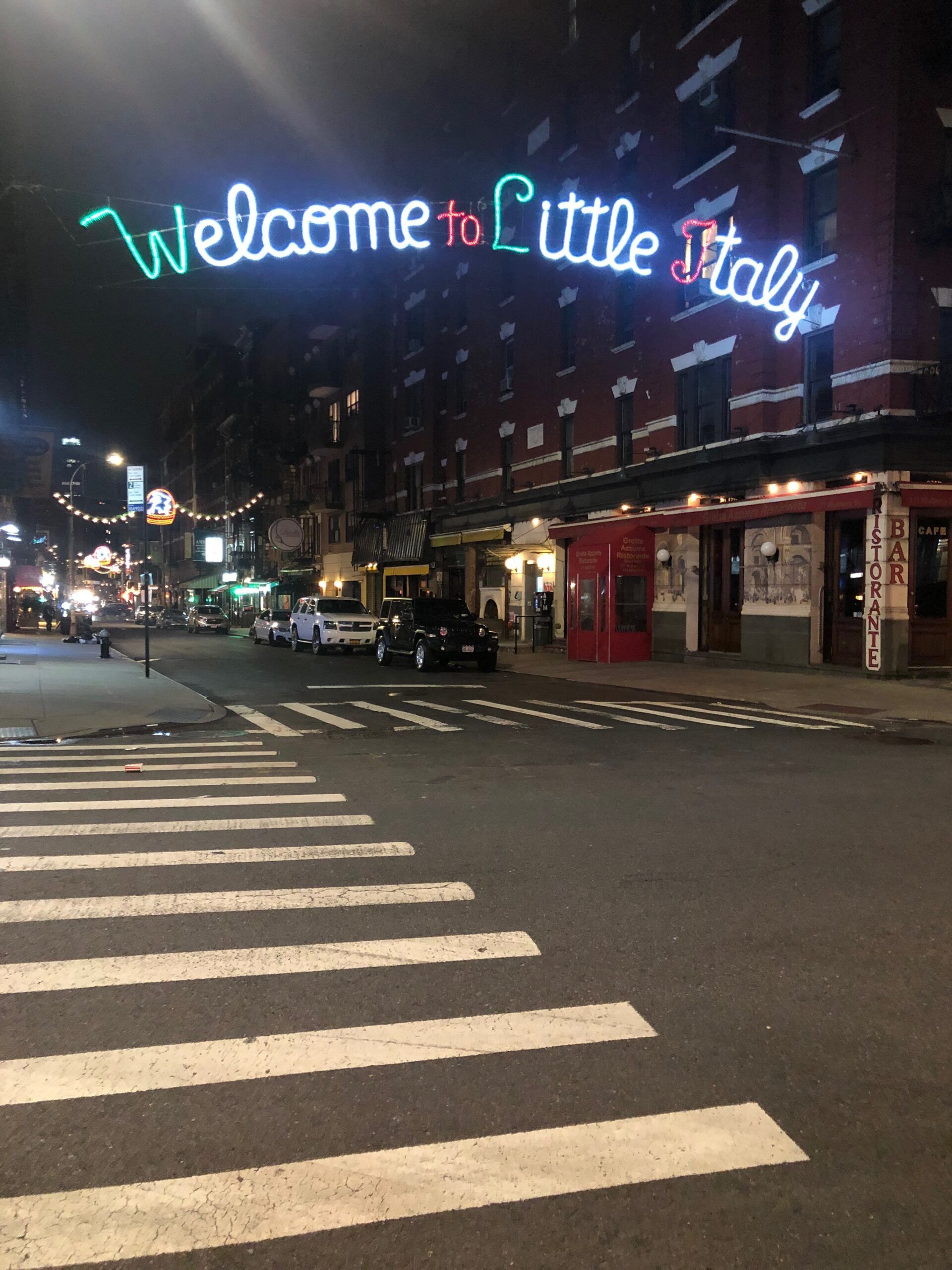 Neonowy napis welcome to little italy nad ulicą w nowym jorku nocą