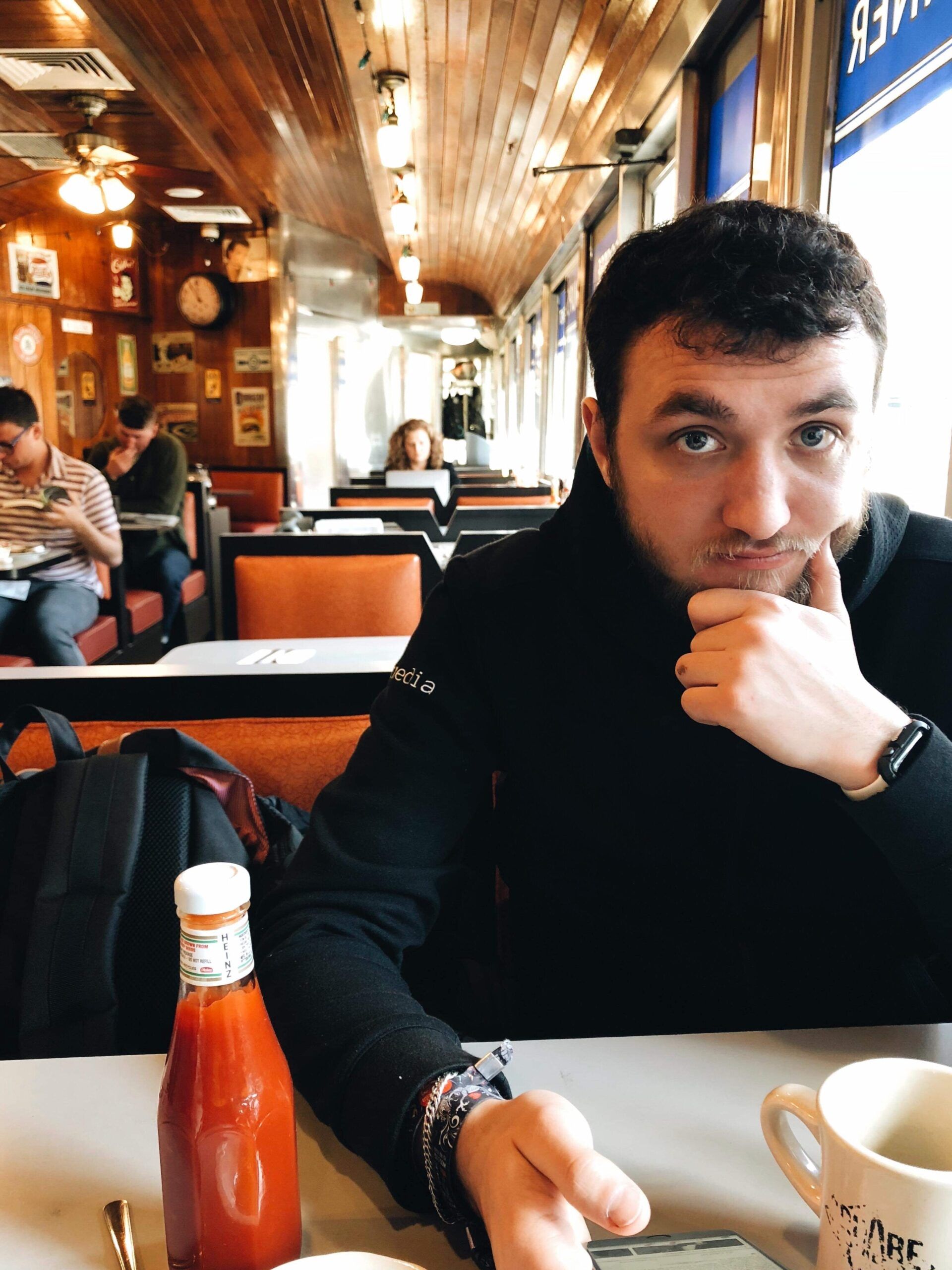 Mężczyzna siedzi w restauracji w nowym jorku przy stole z ketchupem i kubkiem kawy.