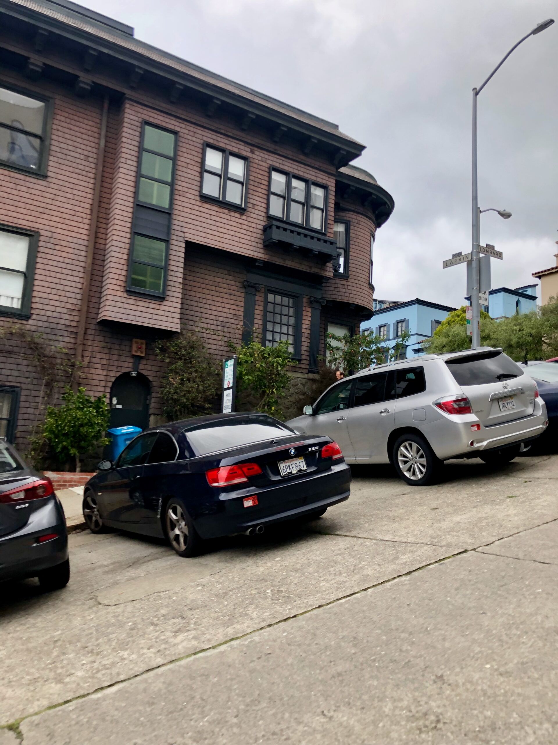 Uliczne skrzyżowanie larkin i lombard w san francisco, z zaparkowanymi samochodami i zabytkową kamienicą.