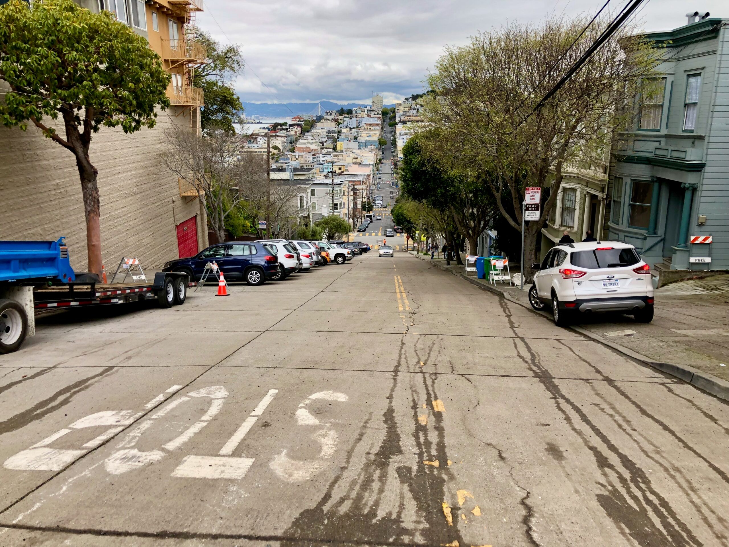 Stroma ulica w san francisco z zaparkowanymi autami i widokiem na wzgórza.