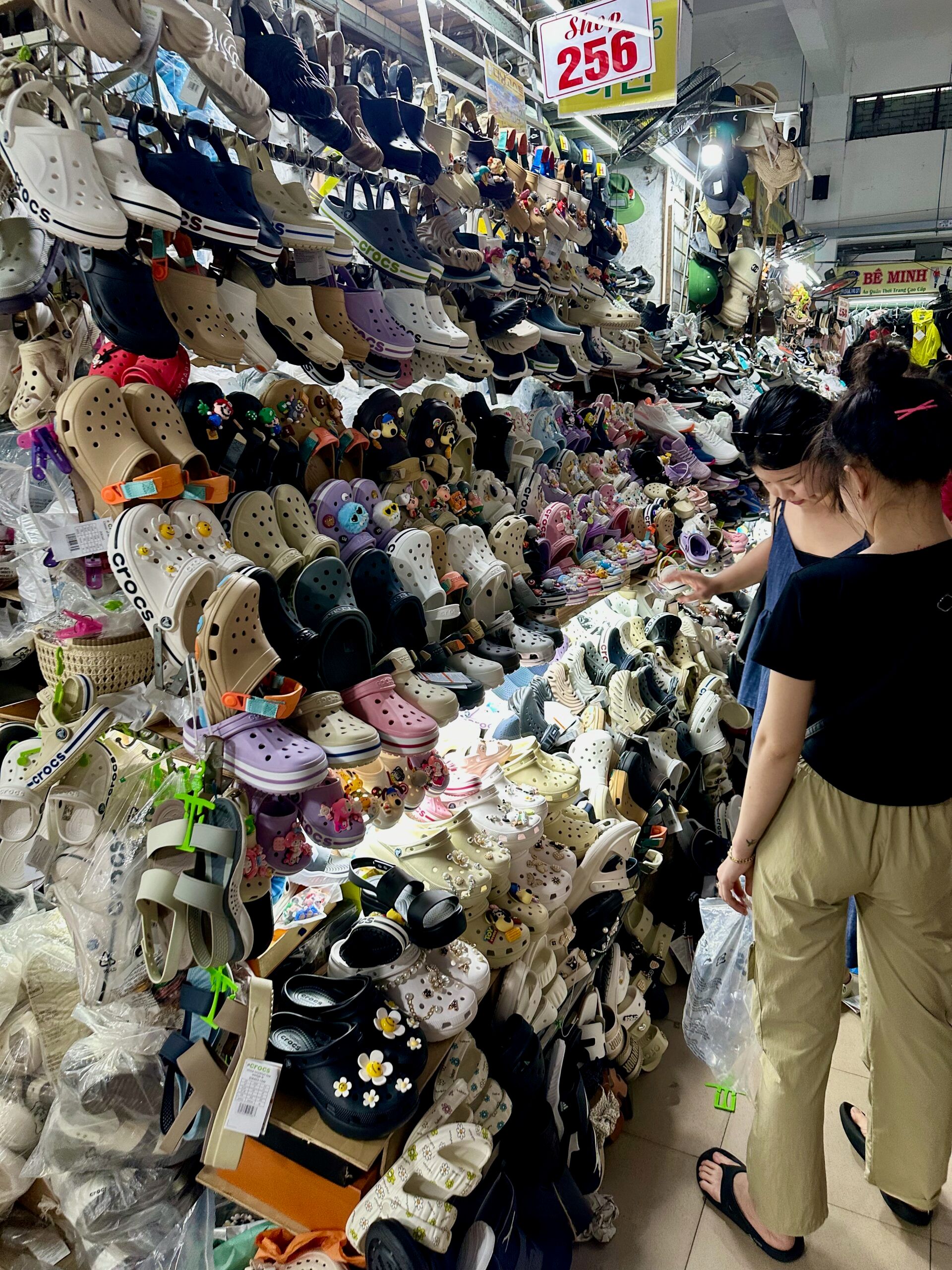 Stoisko z kolorowymi butami w han market w da nang, oglądane przez dwie kobiety.