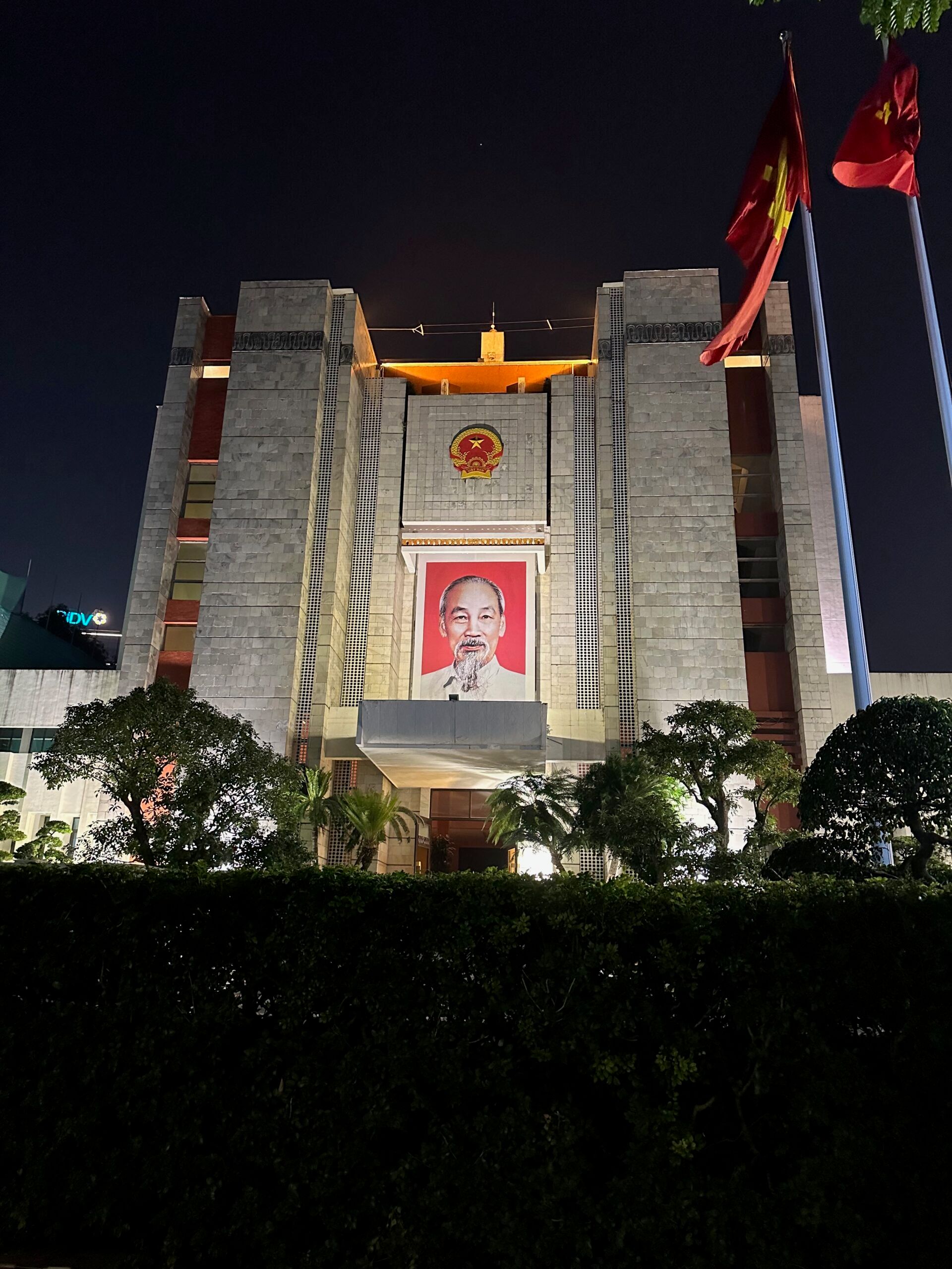 Budynek z portretem hồ chí minha w hanoi nocą, z czerwonymi flagami przed wejściem