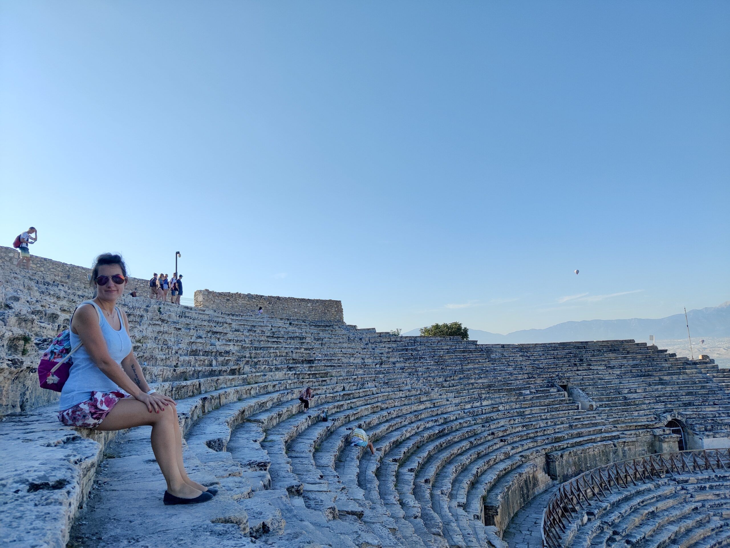 Amfiteatr hierapolis w pamukkale w turcji z siedzącą kobietą na kamiennych trybunach.