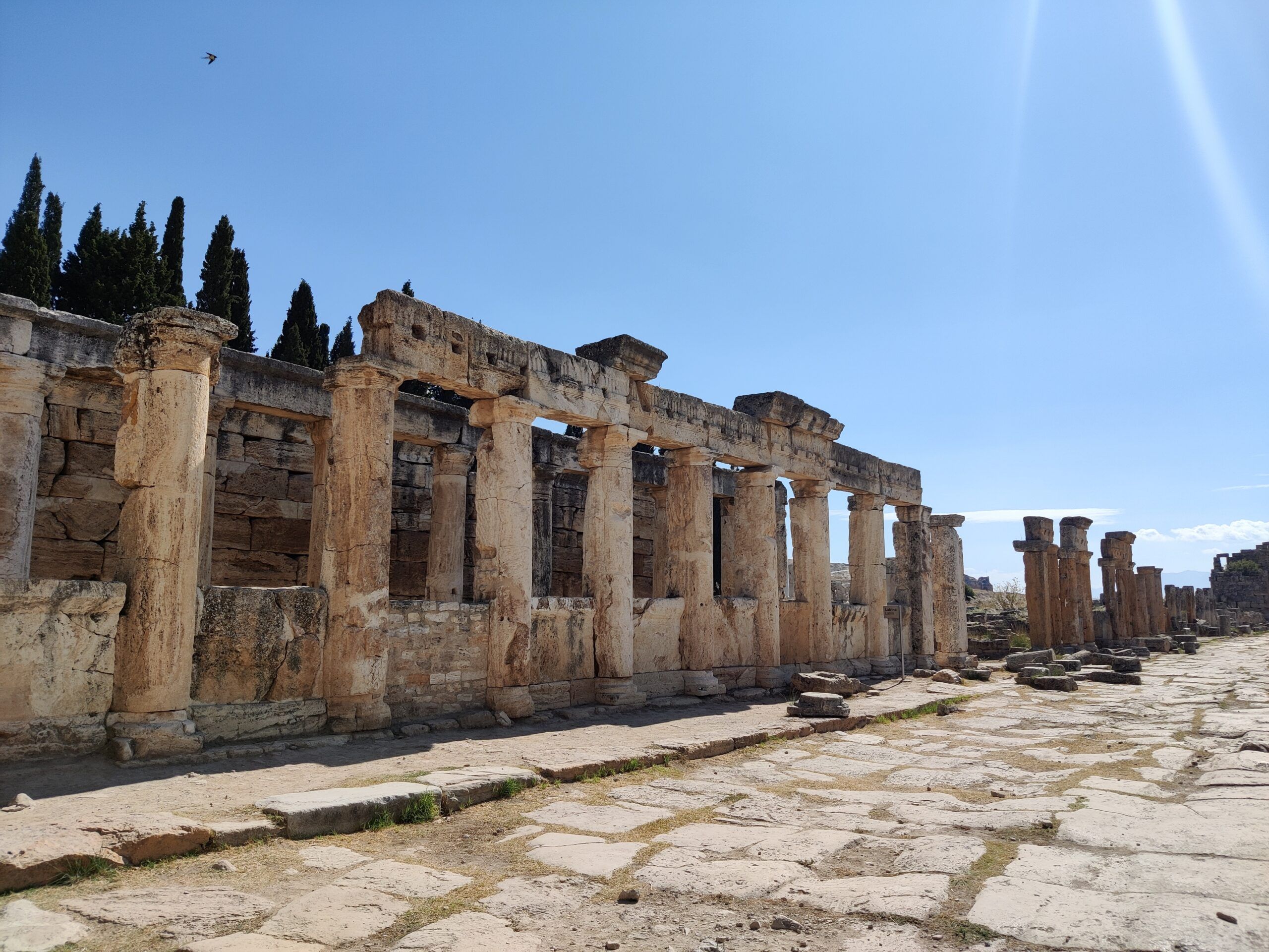 Ruiny nekropolii hierapolis w pamukkale z kamienną kolumnadą i brukowaną drogą pod błękitnym niebem