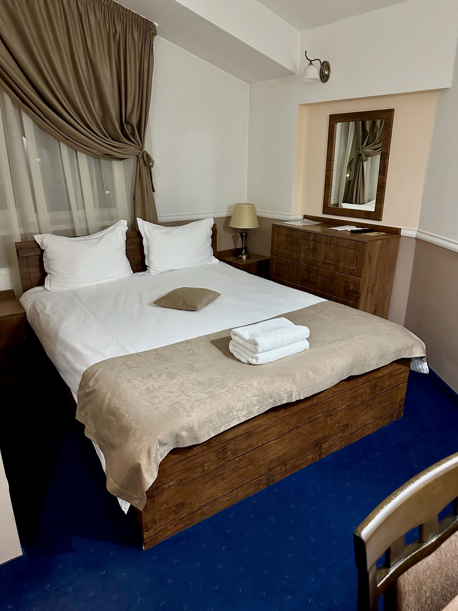 Moldova, chisinau hotel: tidy bedroom with a double bed, bedside lamp, and mirrored dresser